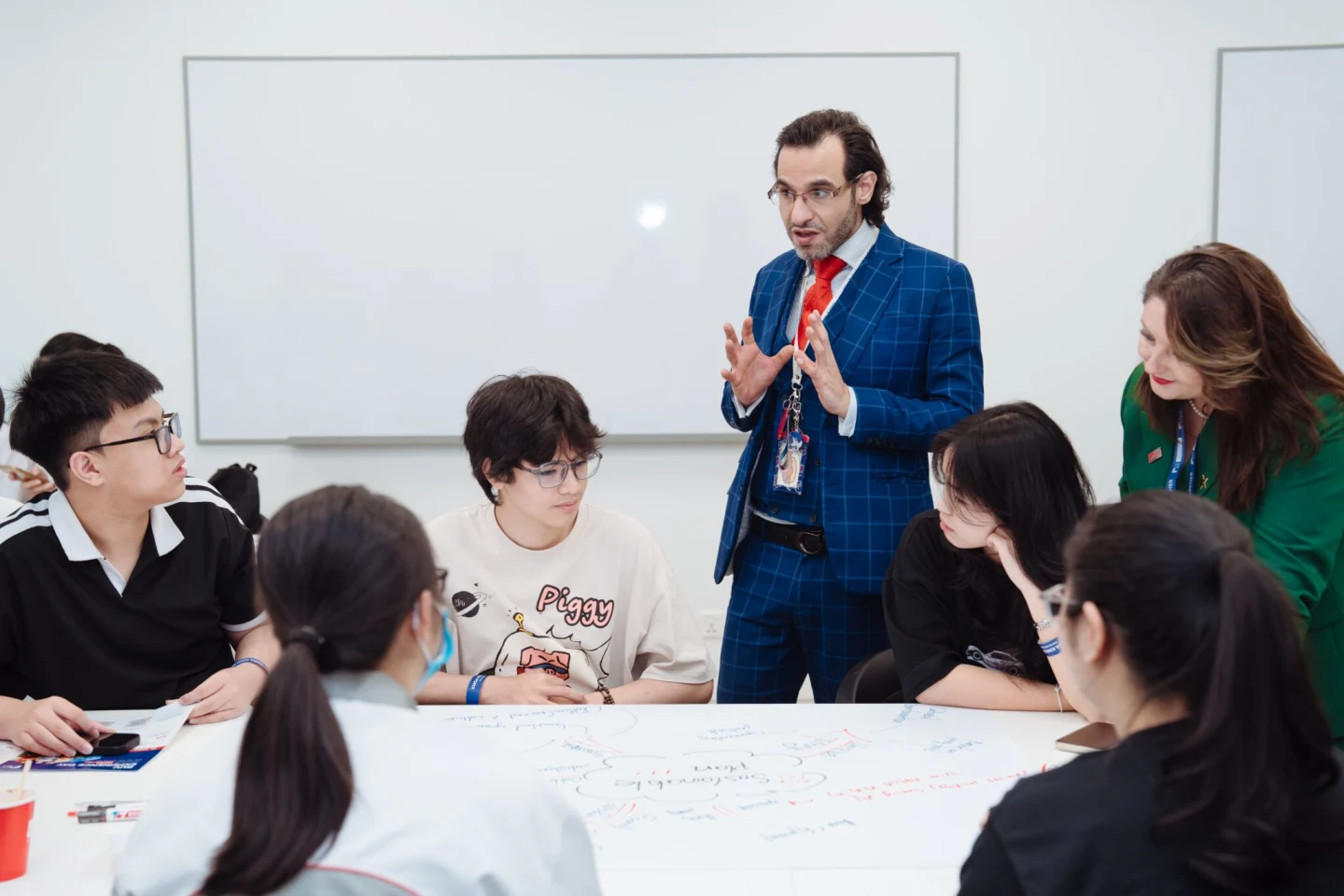 A lecturer leads an interactive classroom discussion with students seated around a table at BUV.