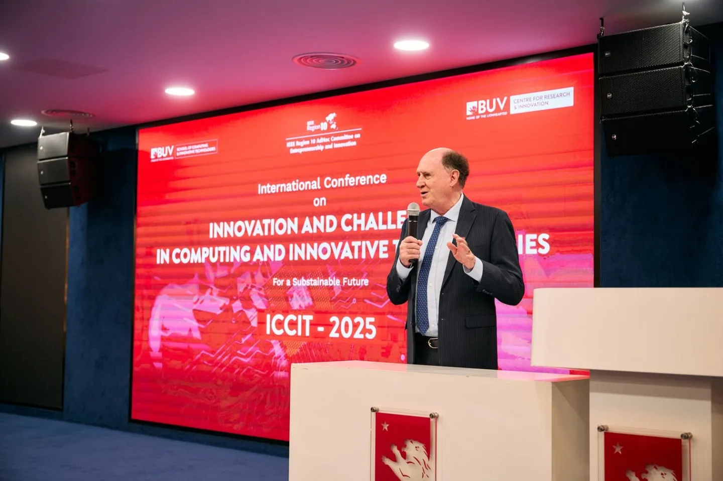 A suited speaker addresses the audience at the ICCIT 2025 International Conference on innovation and challenges in computing and innovative technologies.