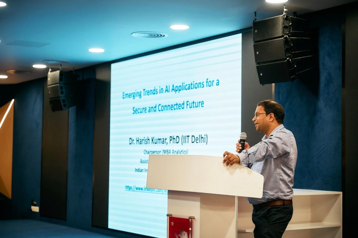 A guest speaker presents “Emerging Trends in AI Applications for a Secure and Connected Future” from a podium in a university lecture hall.