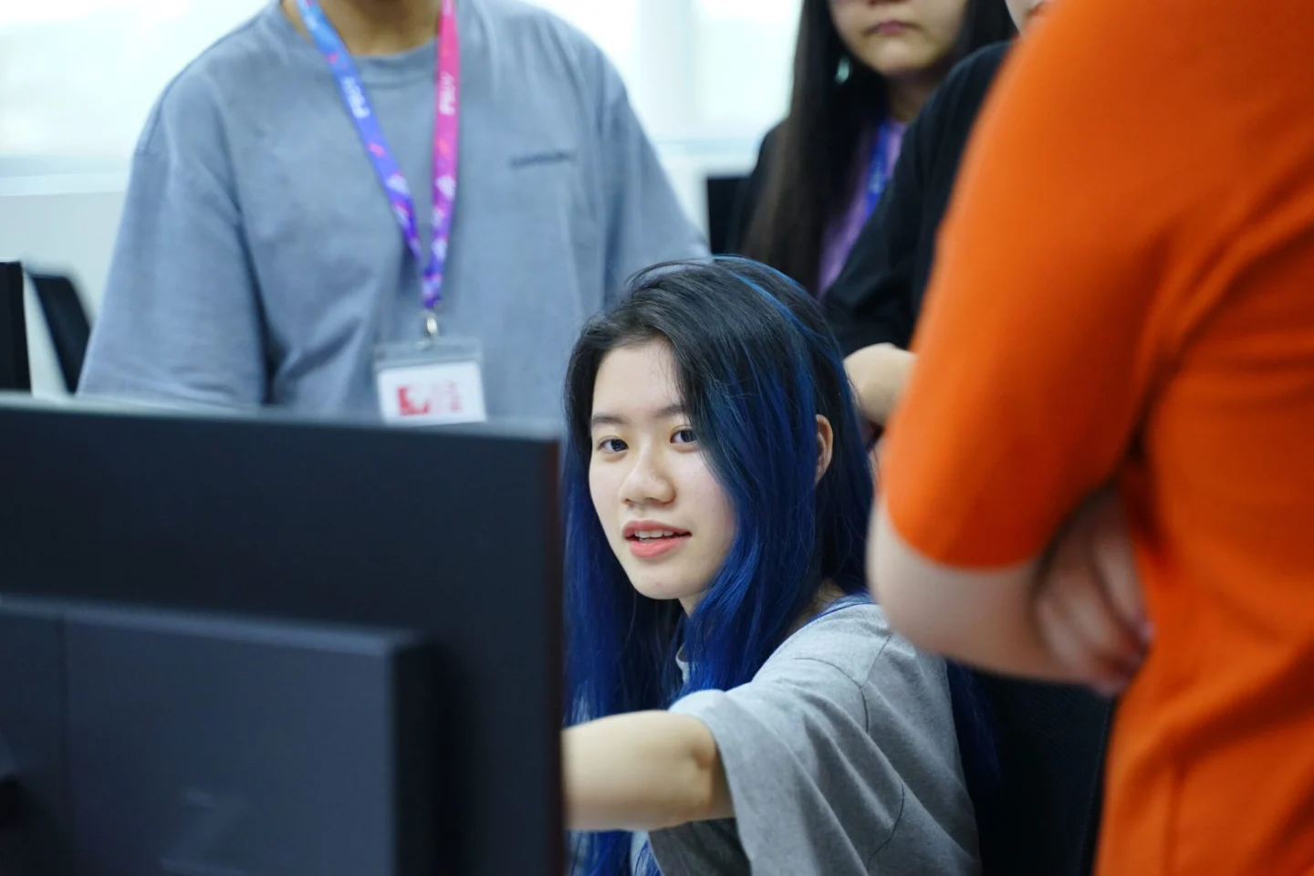 A student works at a computer while staff members observe in a classroom or laboratory setting.