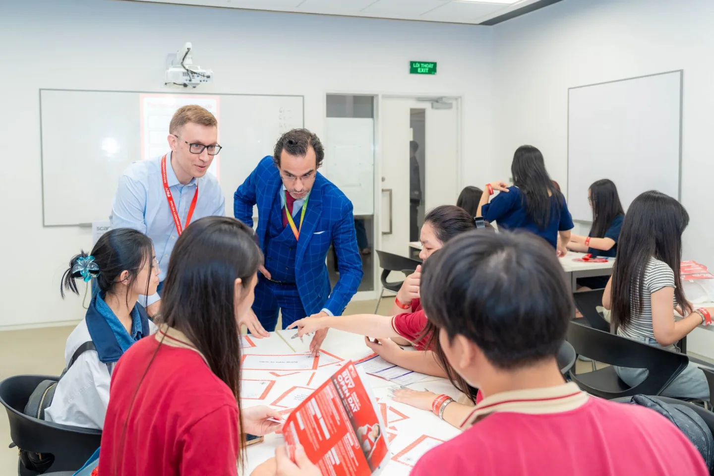 Two instructors guide students working in groups on a collaborative classroom activity at BUV.