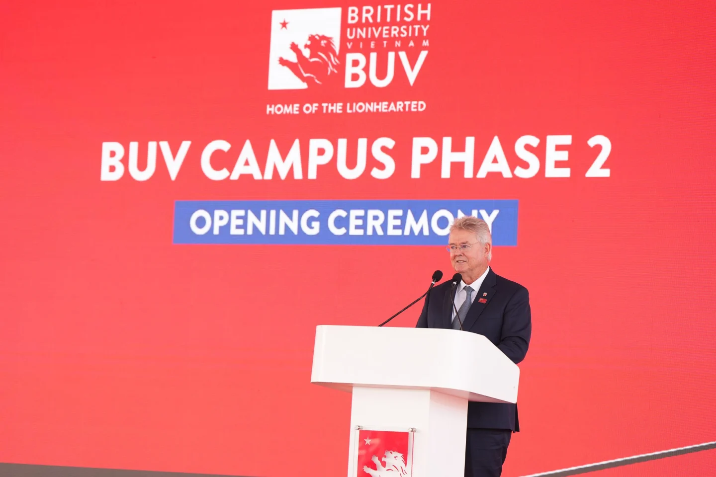 A speaker delivers remarks at a podium during the BUV Campus Phase 2 opening ceremony.