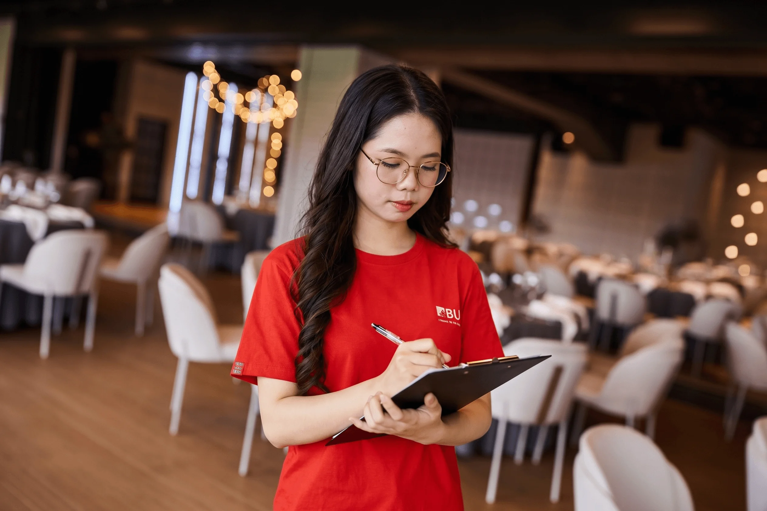 BUV hospitality management student taking notes during practical training in a professional restaurant
