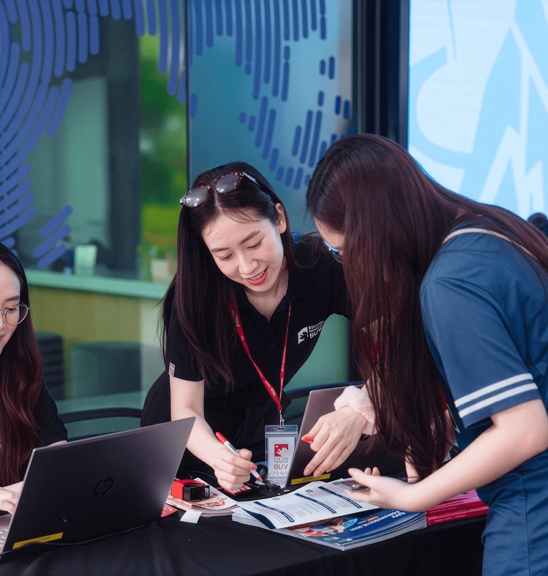 BUV students collaborating at an international education event with laptops and university brochures.