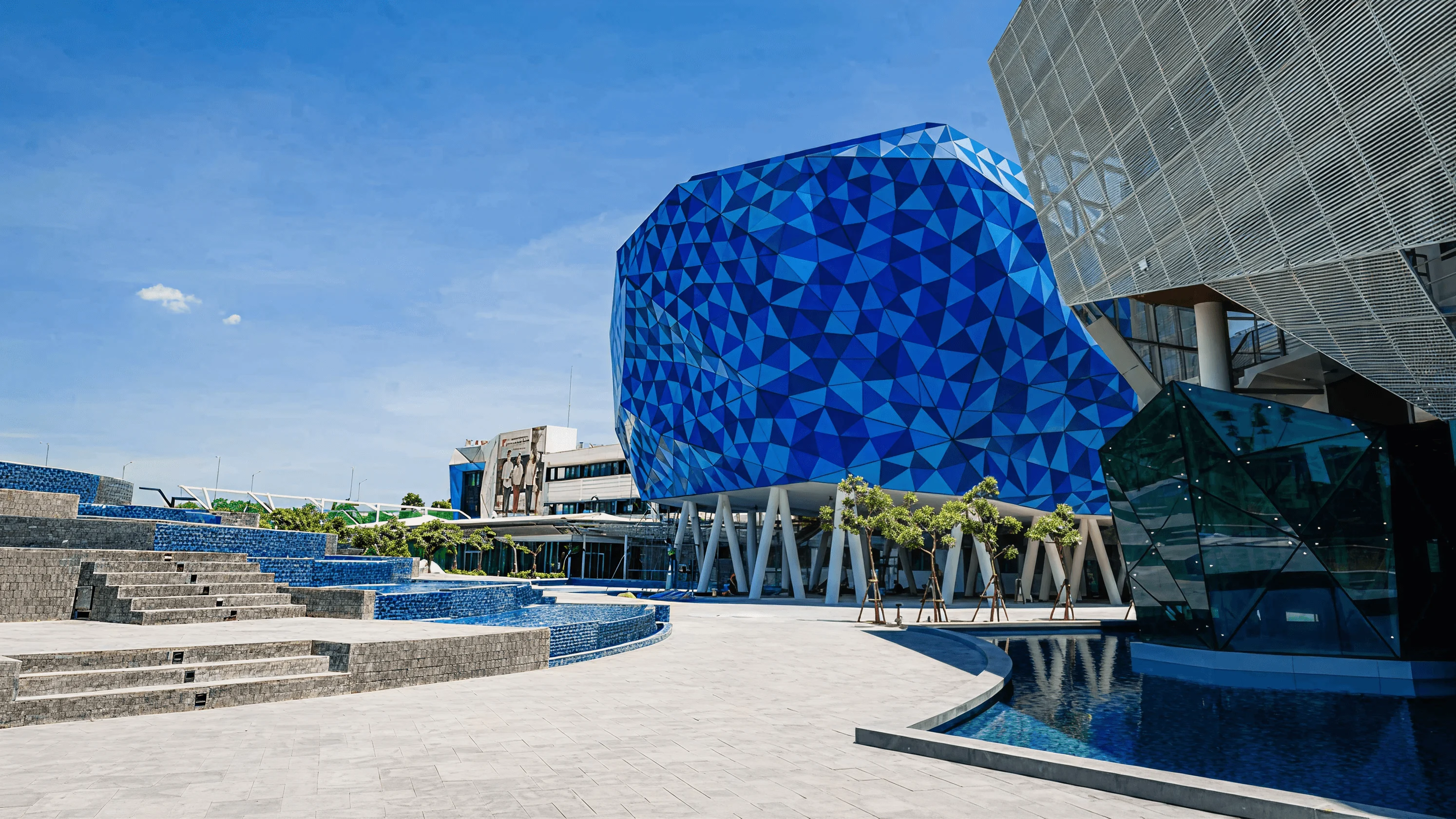 BUV campus facilities with a striking blue geometric building, landscaped plaza, stepped seating and reflecting pools