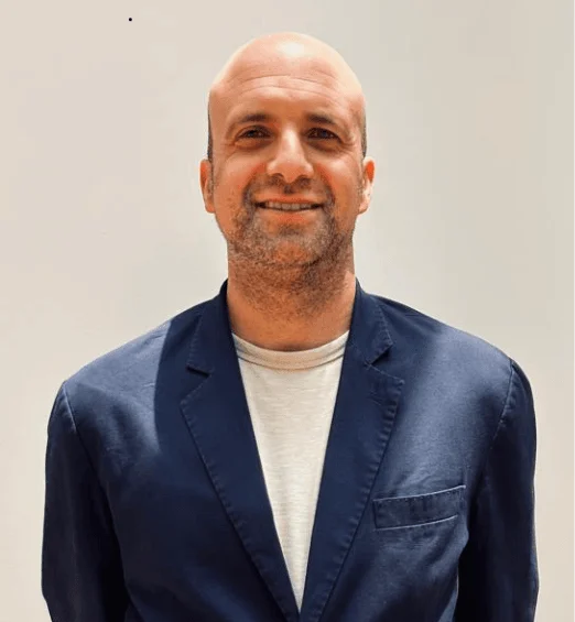 Umberto De Vita smiling in a navy blazer and white shirt, professional portrait for BUV
