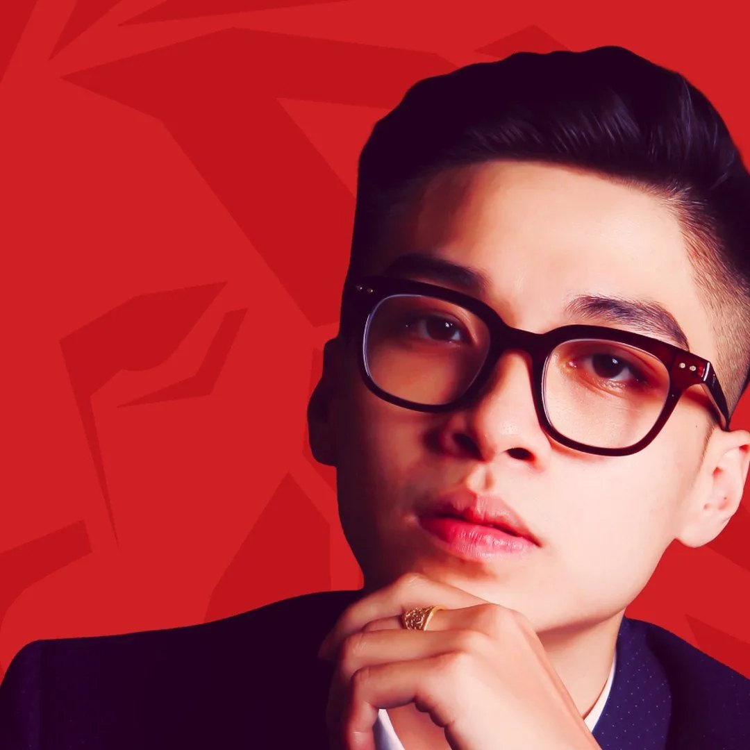 BUV alumnus Nhật Anh in glasses and a dark suit against a red background.