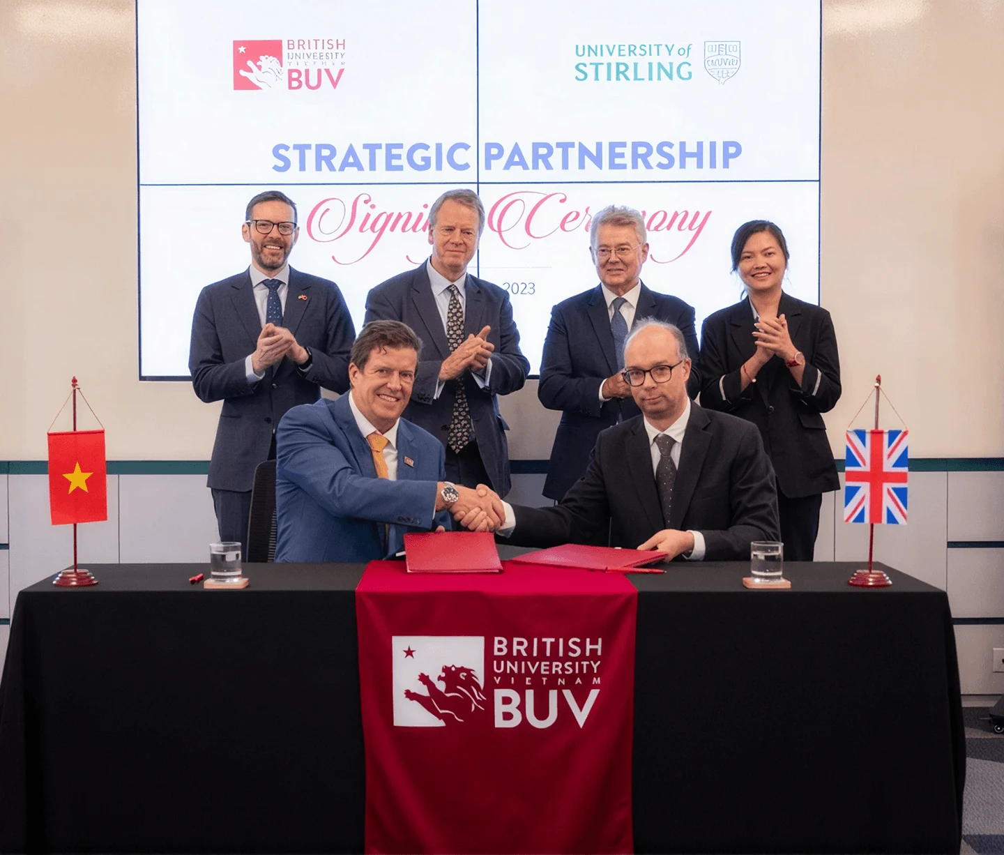 BUV and University of Stirling strategic partnership signing ceremony with officials shaking hands and Vietnam-UK flags