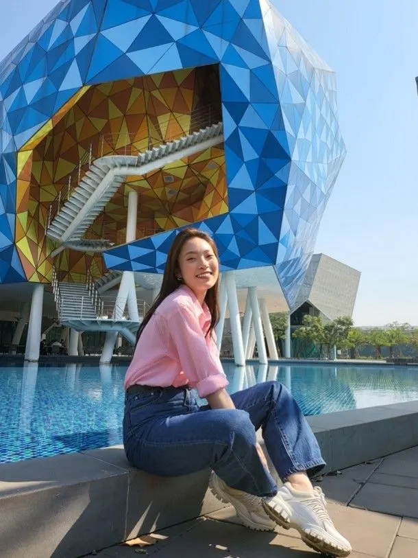 Khanh Vy sits beside a pool outside BUV’s modern blue geometric campus building.