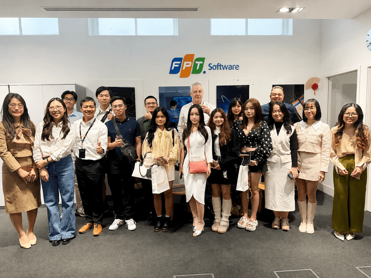 A group of students and professionals smiling and posing together in front of the FPT Software logo during an industry visit.