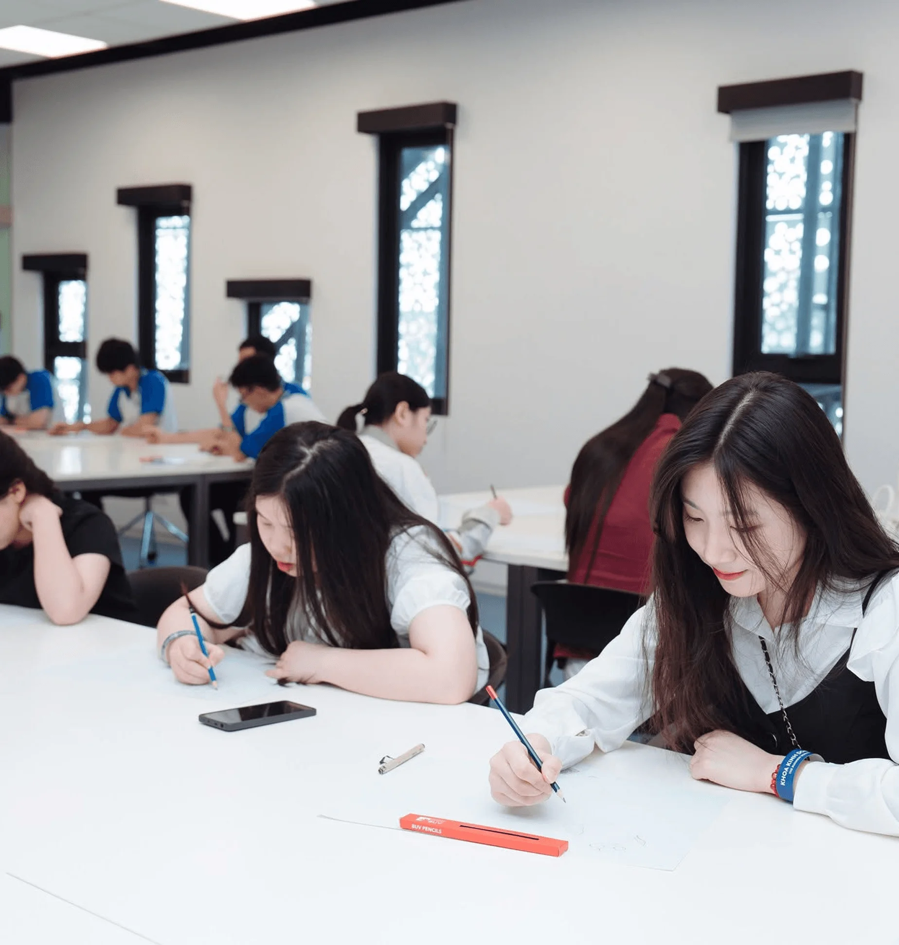 British University Vietnam students studying and writing in a bright classroom