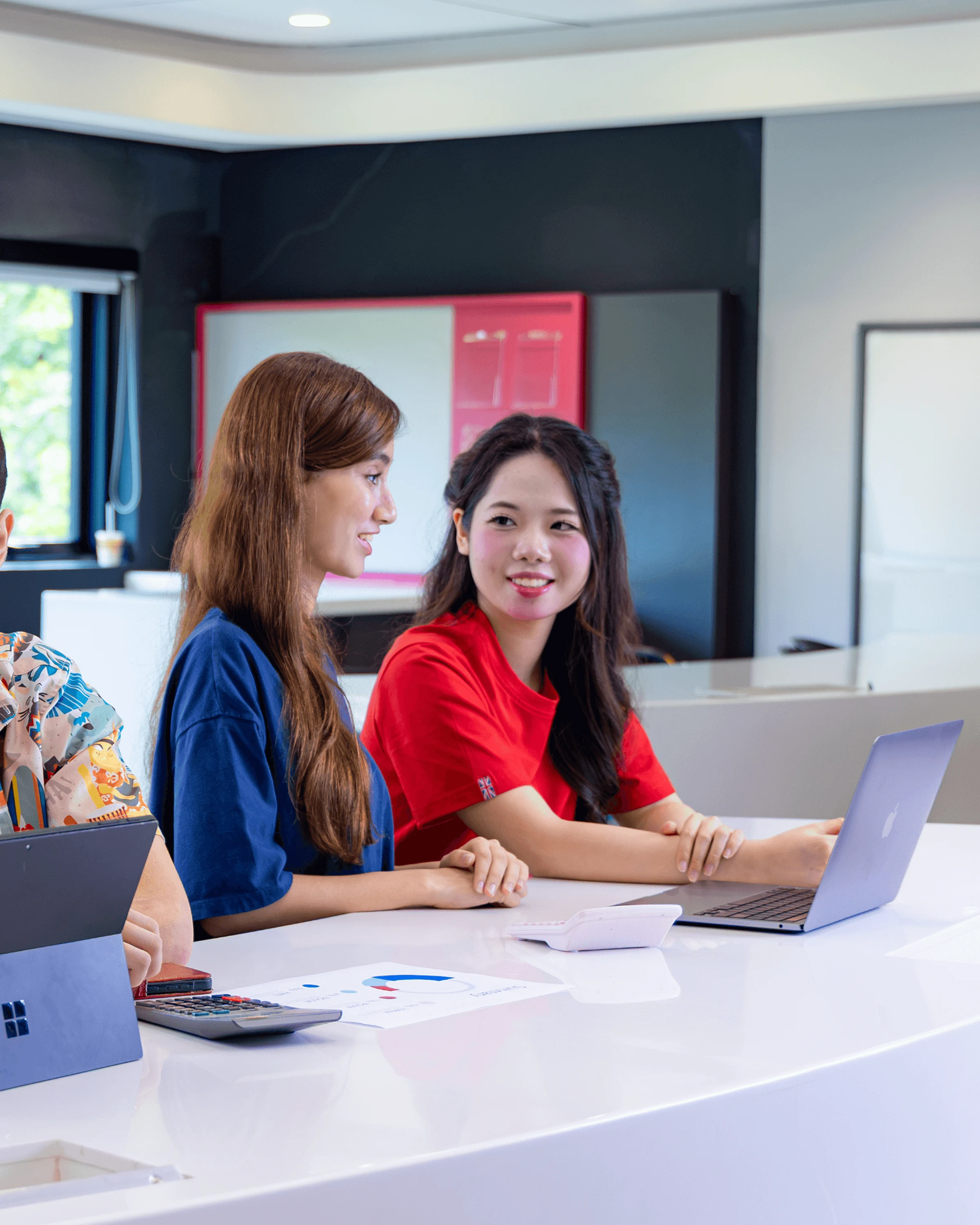 British University Vietnam students collaborating with laptops and charts in a modern classroom