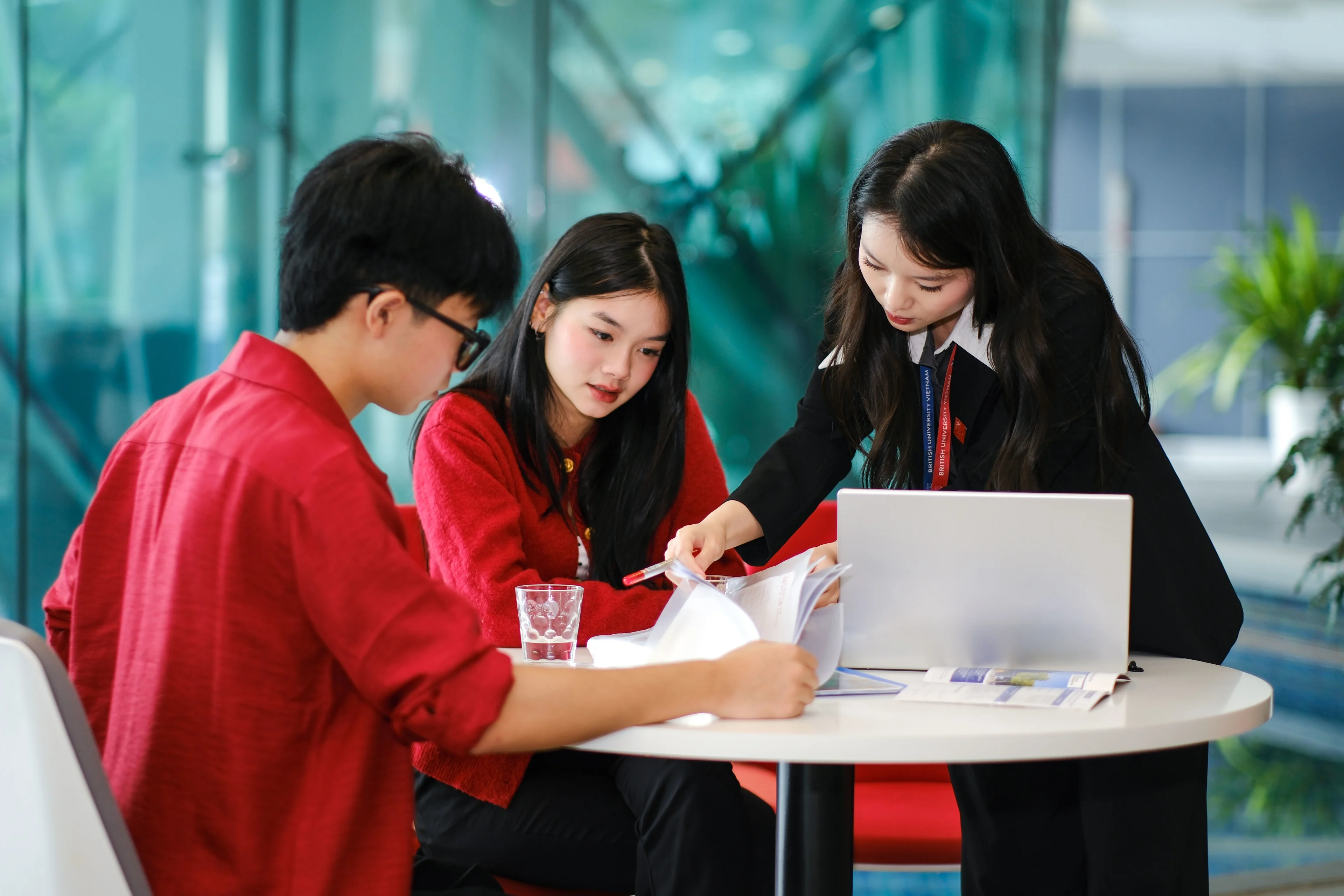 British University Vietnam students collaborating on coursework with a laptop in a modern campus study area
