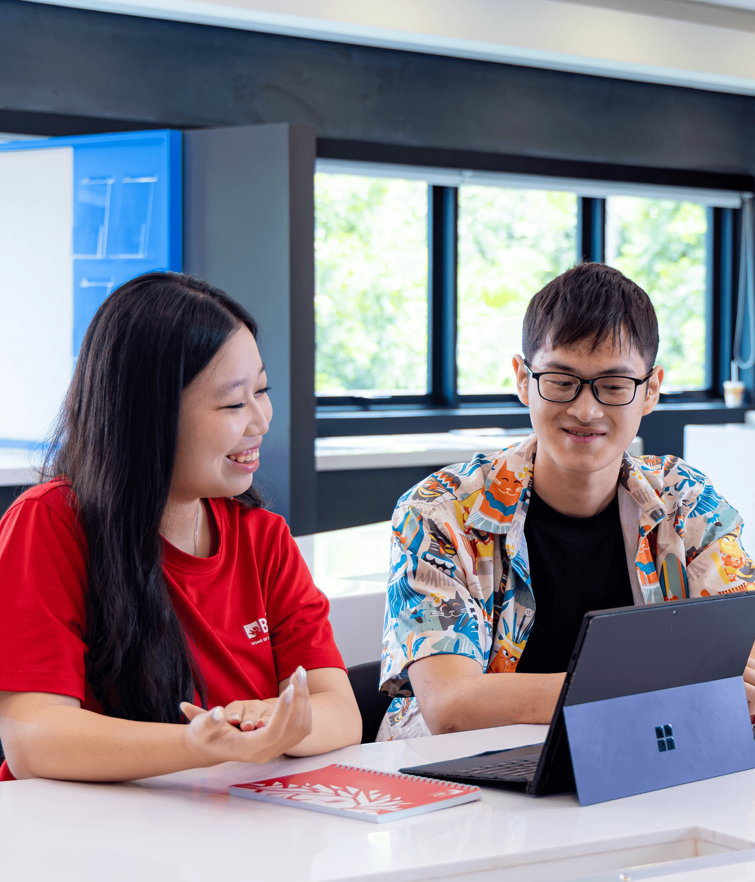 British University Vietnam students collaborating on a Microsoft Surface tablet in a modern classroom