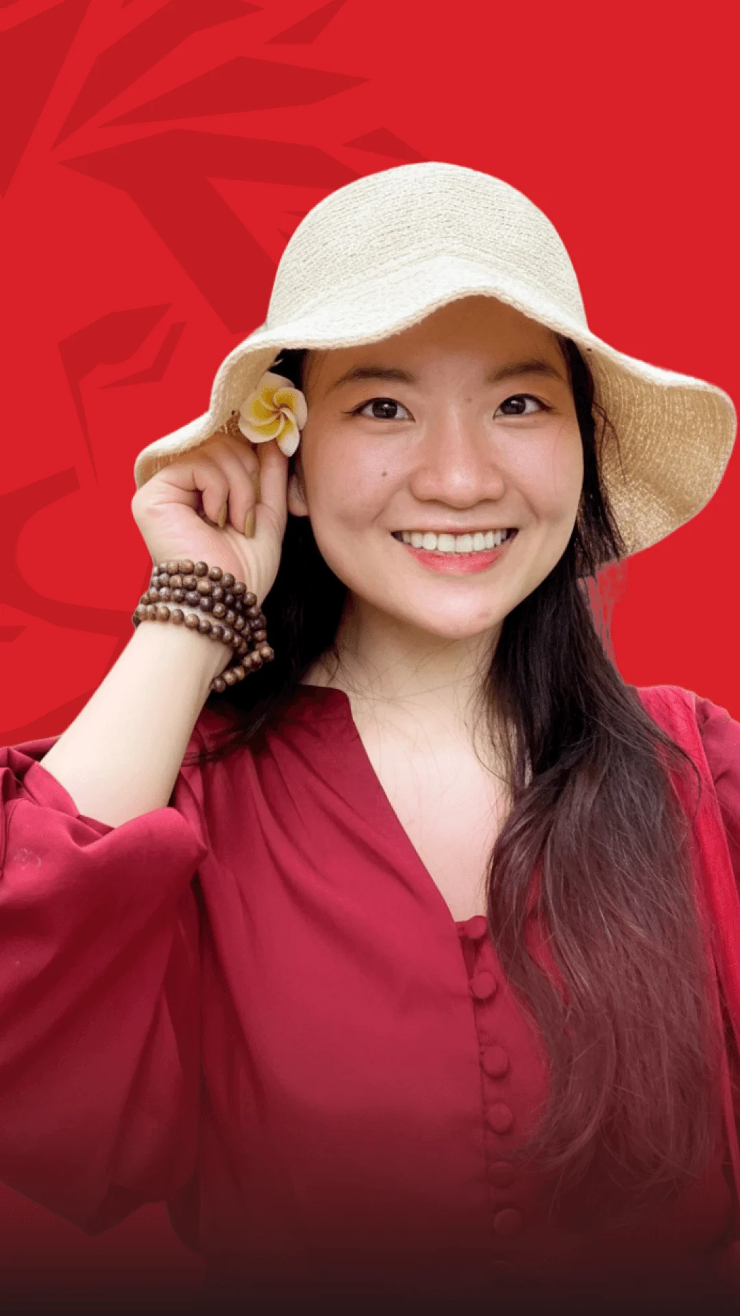 Smiling alumna wearing a wide-brim hat and a red outfit, with a red background.