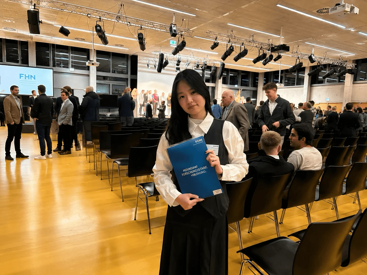 BUV student holding a blue programme booklet at an international university transfer and career event.