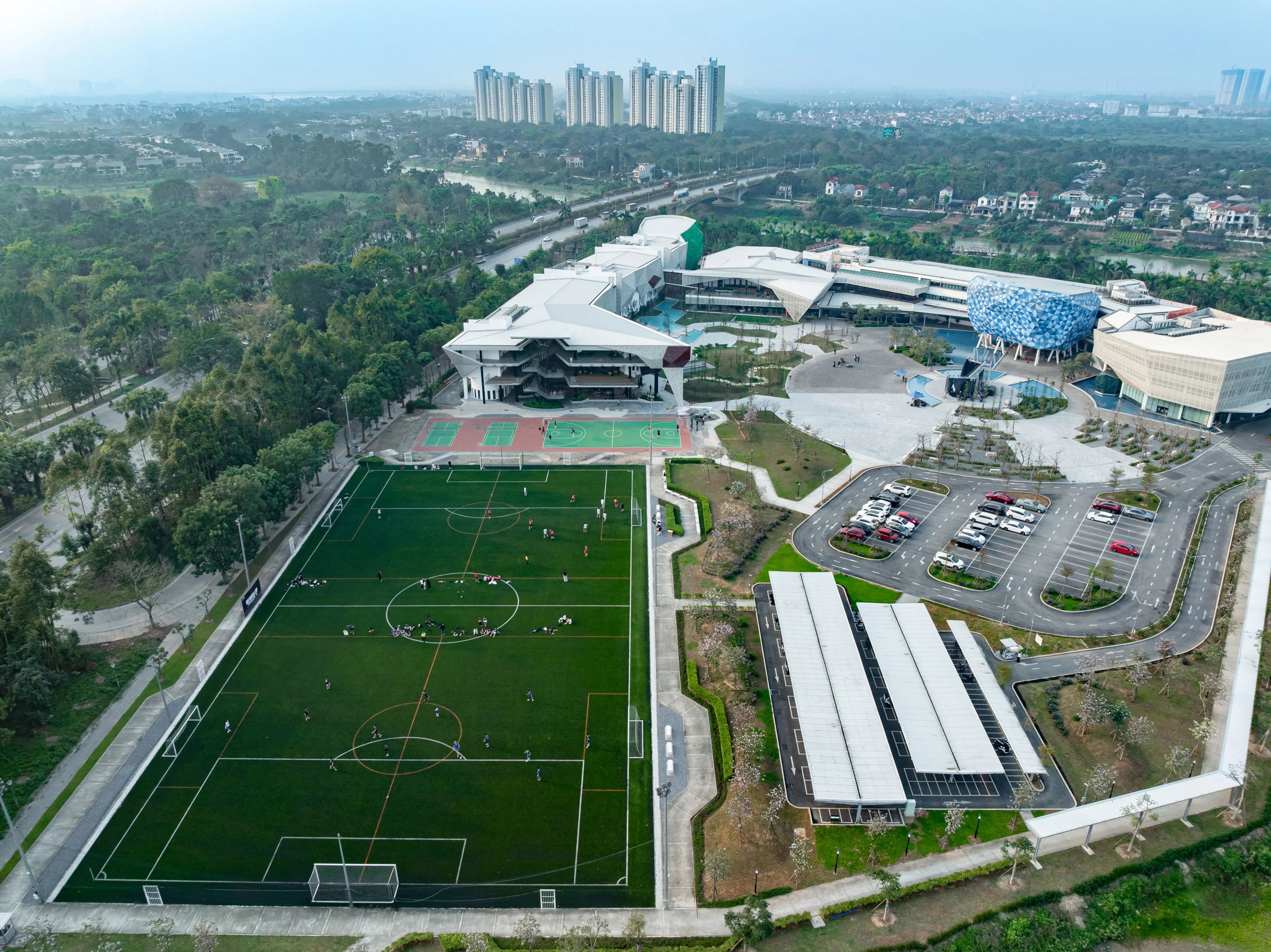 Aerial view of BUV campus in Vietnam with modern buildings, football fields, sports courts, and landscaped grounds