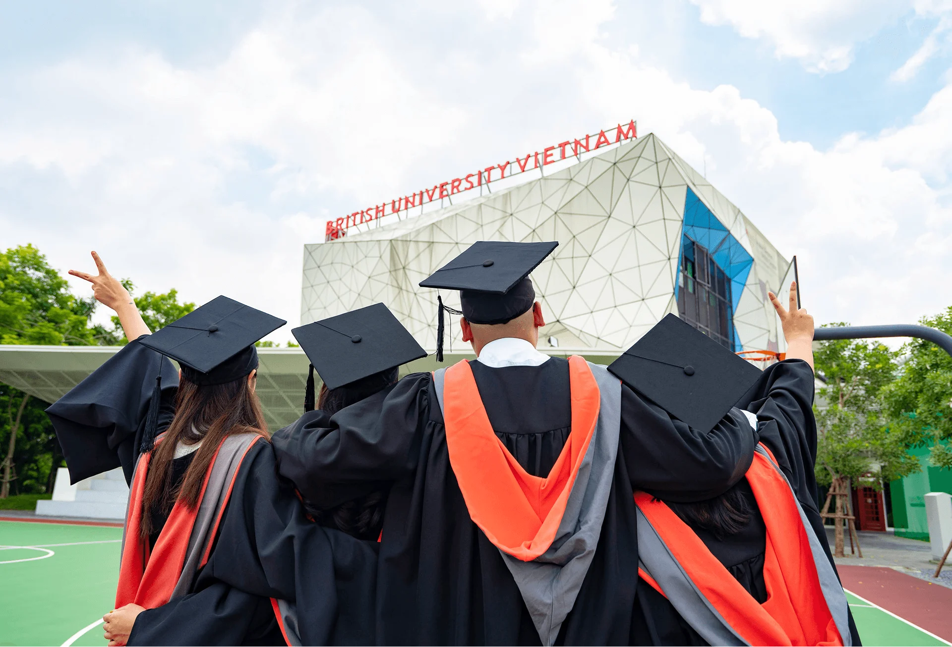 BUV graduates in caps and gowns celebrating outside British University Vietnam campus.