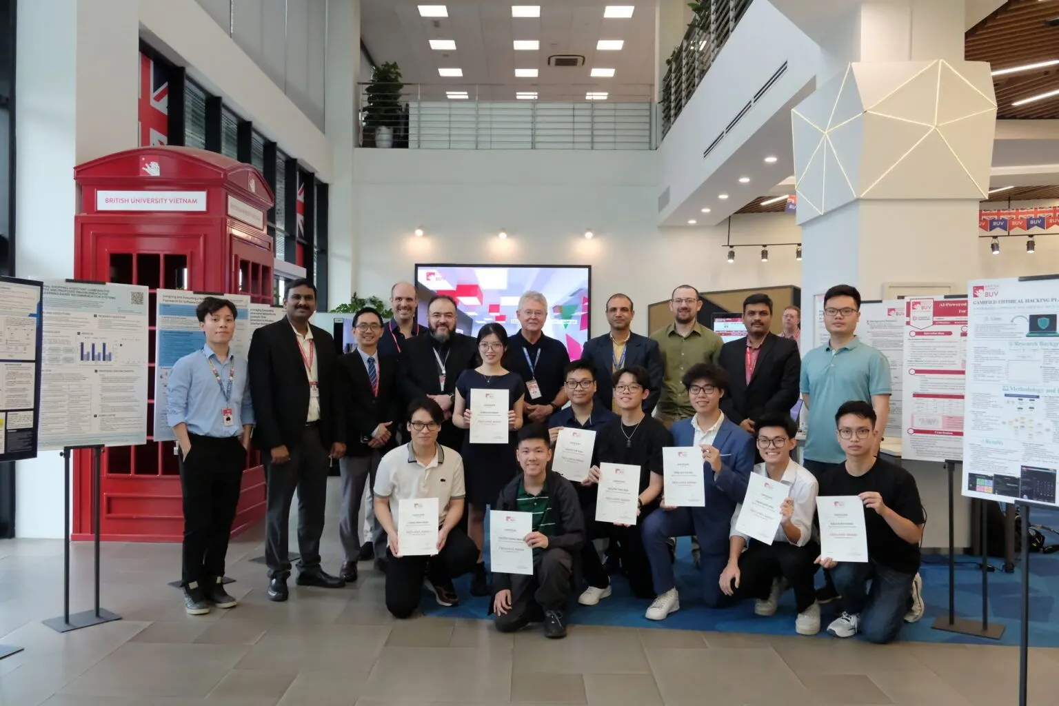 BUV students and faculty holding certificates at a research showcase in the British University Vietnam campus lobby.