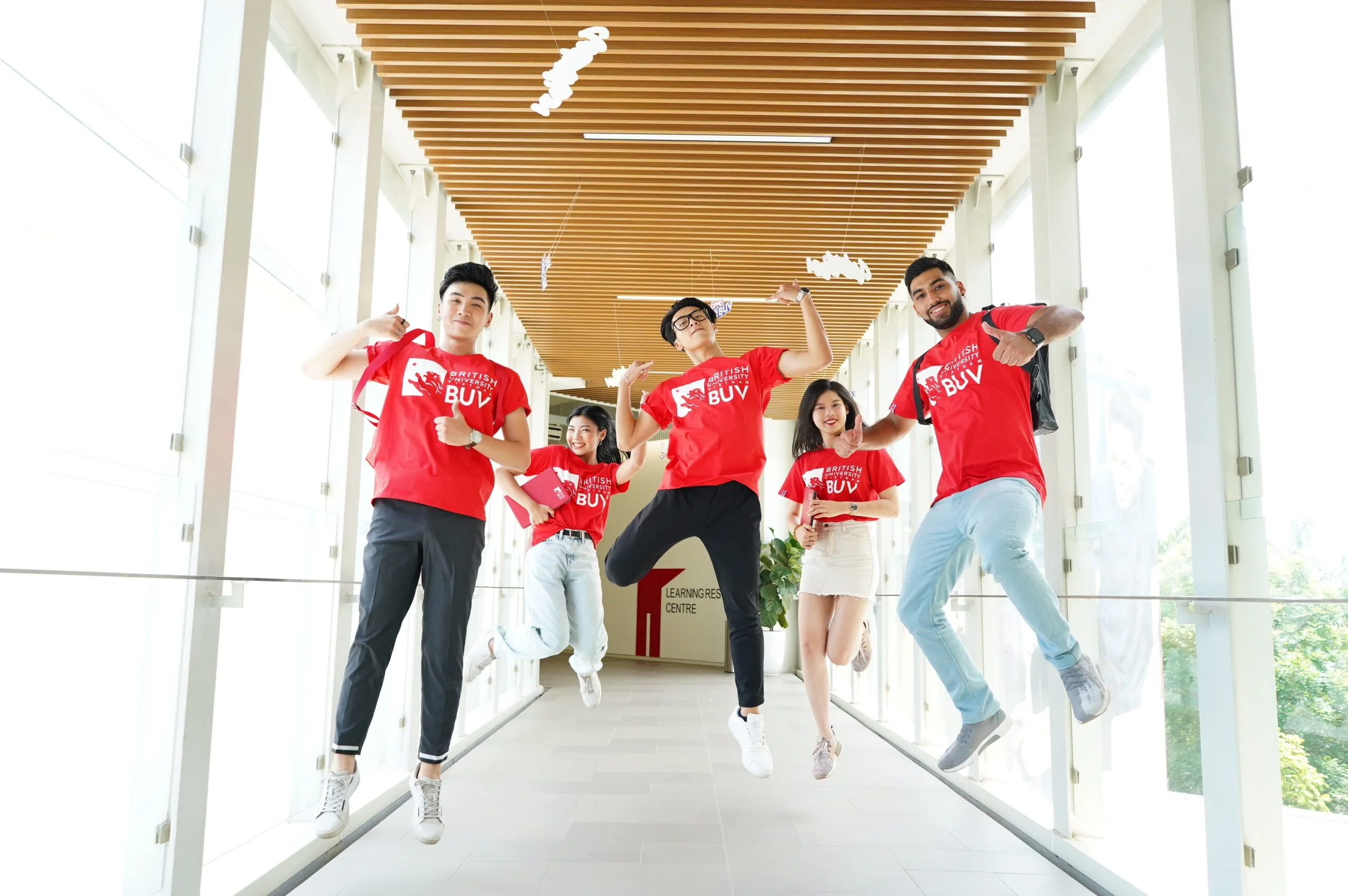 BUV students jump joyfully in red shirts, reflecting wellbeing and a vibrant campus community