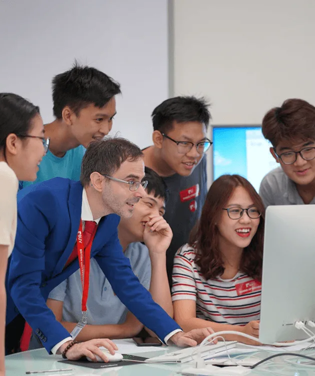 BUV students and staff collaborating on a computer project in a modern classroom.
