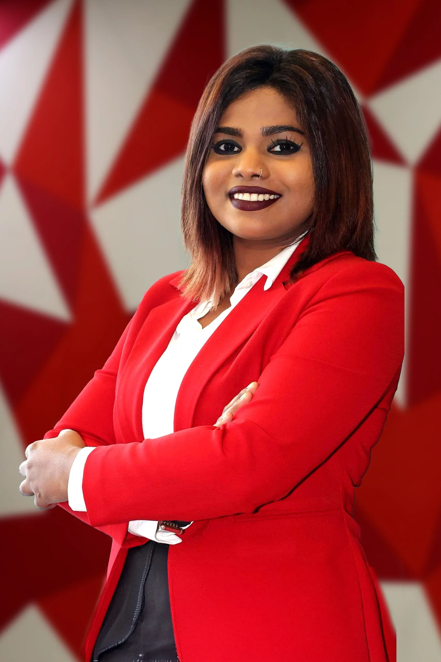 Shruthi Thaiveppil smiling in a red blazer at British University Vietnam, with arms crossed
