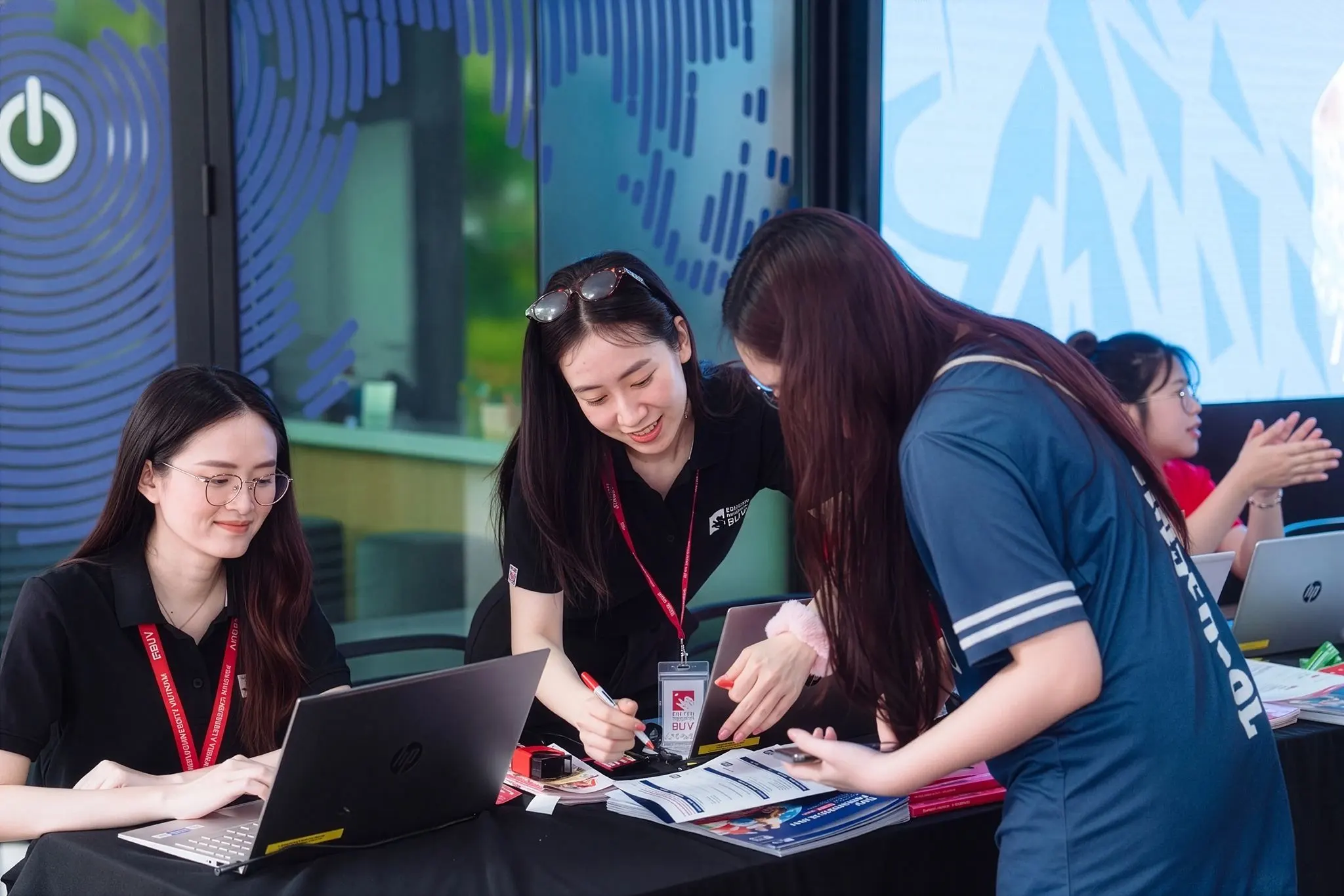 BUV admissions staff assisting a prospective student with application materials at an information desk.