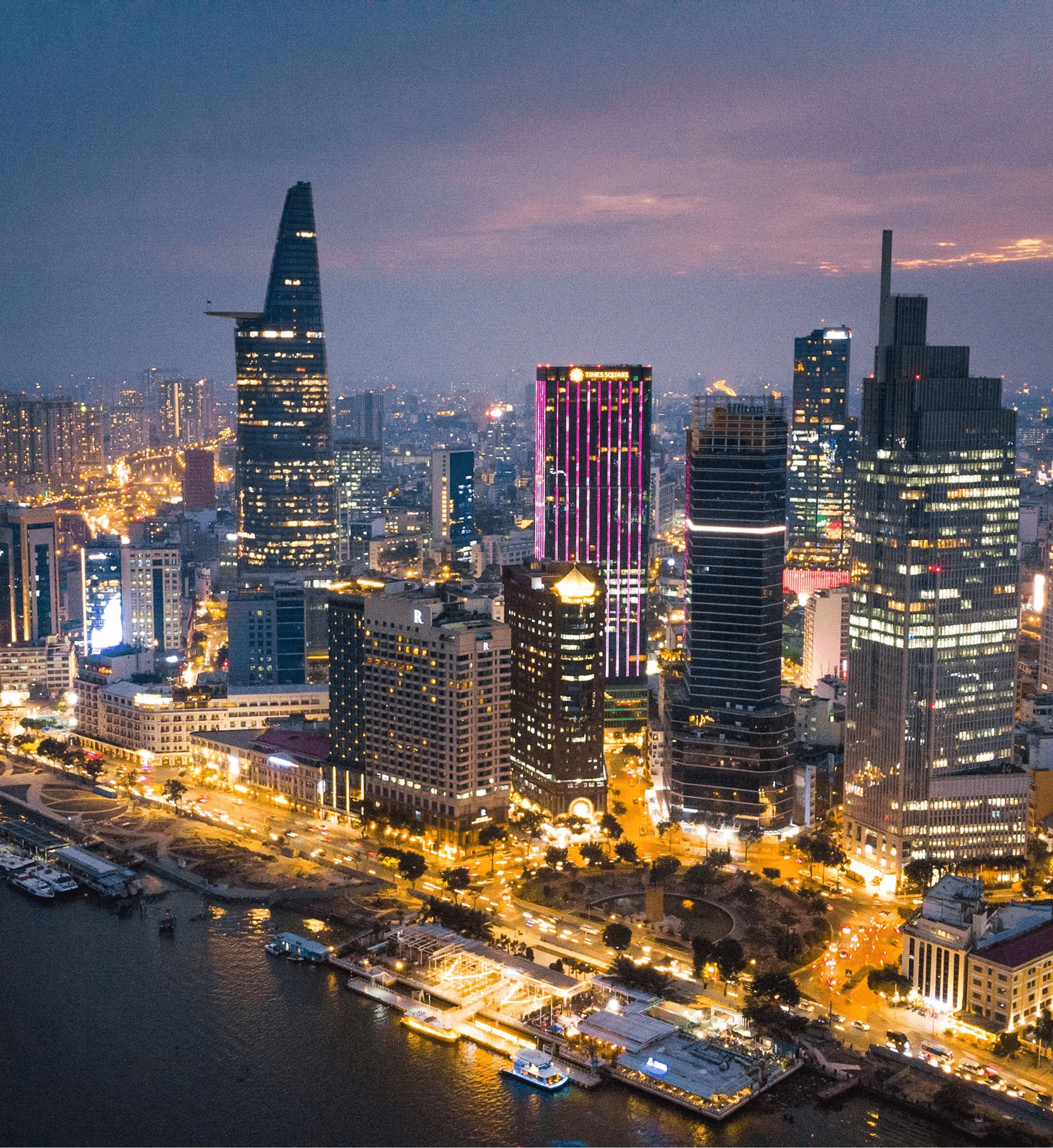 Ho Chi Minh City skyline at dusk with Bitexco Tower, Times Square, and Saigon River waterfront lights