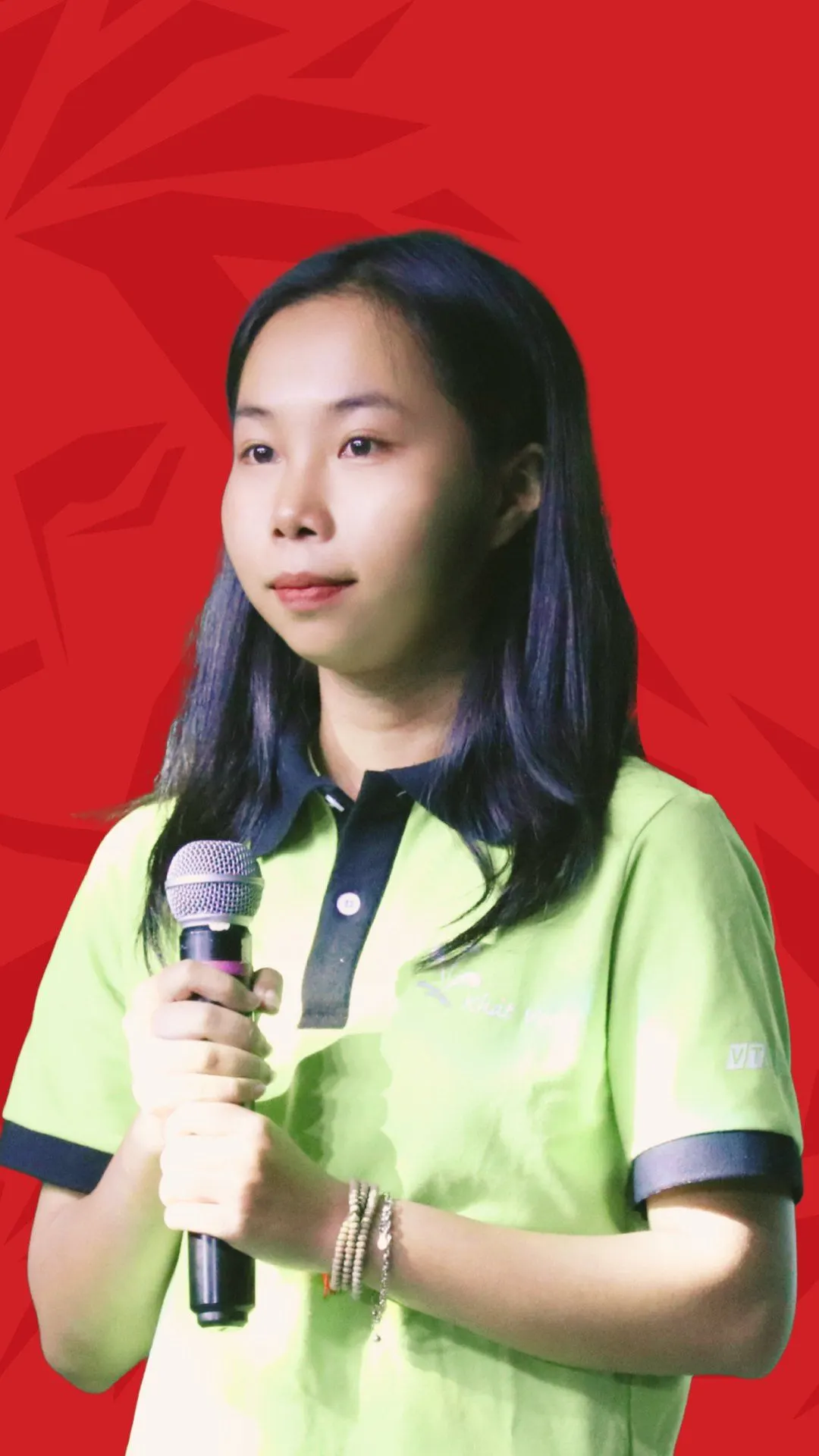 BUV alumna Oanh Nguyen speaking into a microphone against a red background.