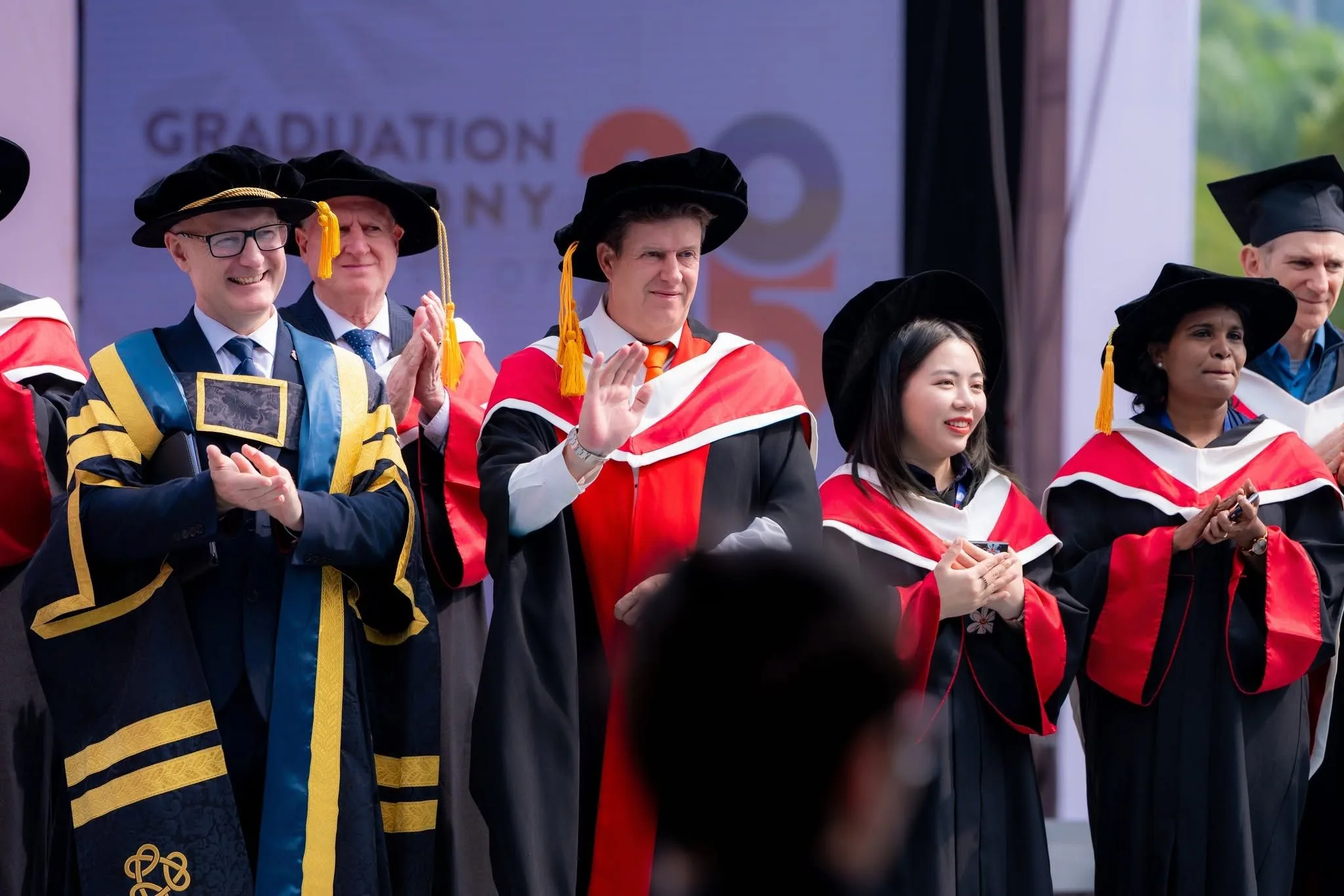 Graduation ceremony with academic staff and graduates in gowns.