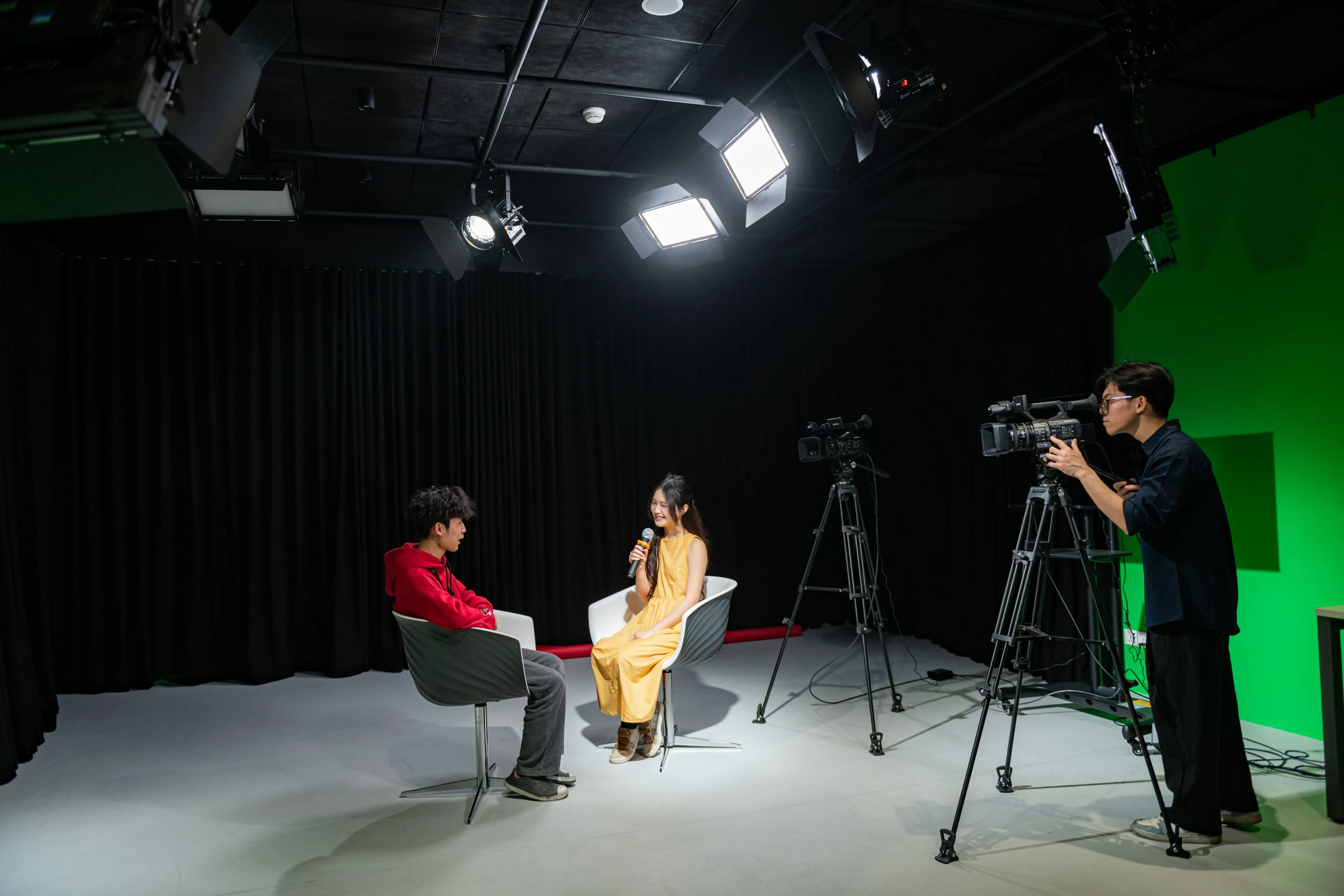 BUV students filming an interview in a professional media studio with cameras, lighting and a green screen