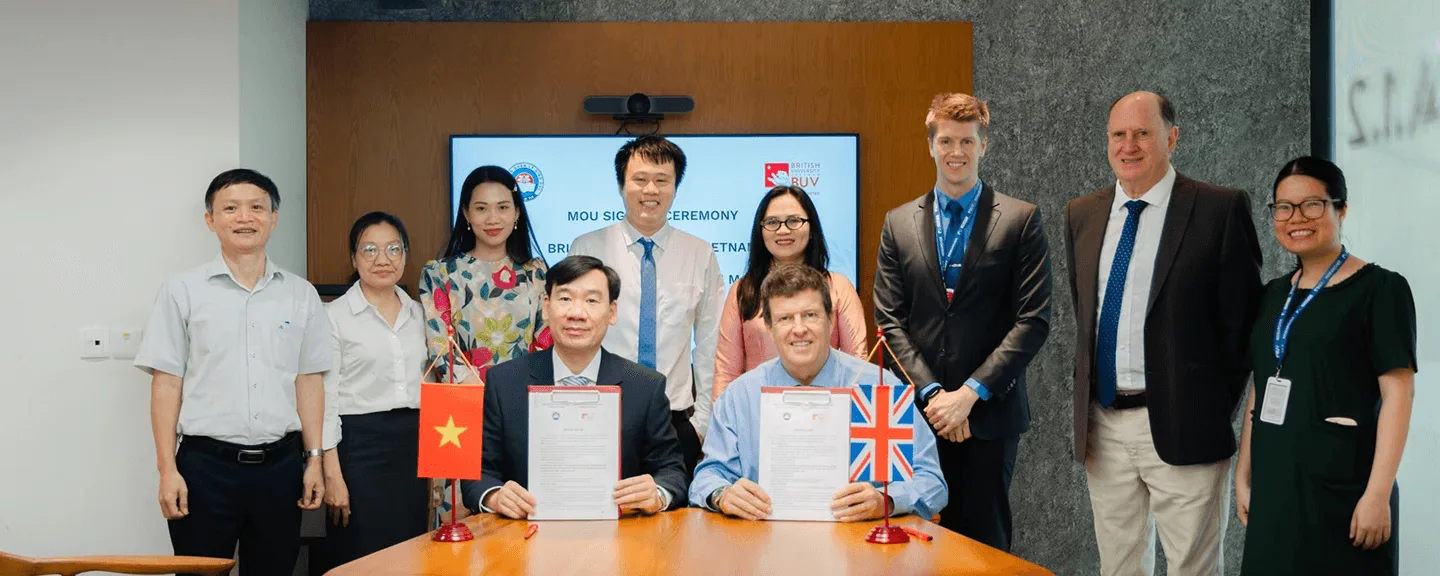 BUV and British university representatives sign an MOU at a ceremony with Vietnam and UK flags.