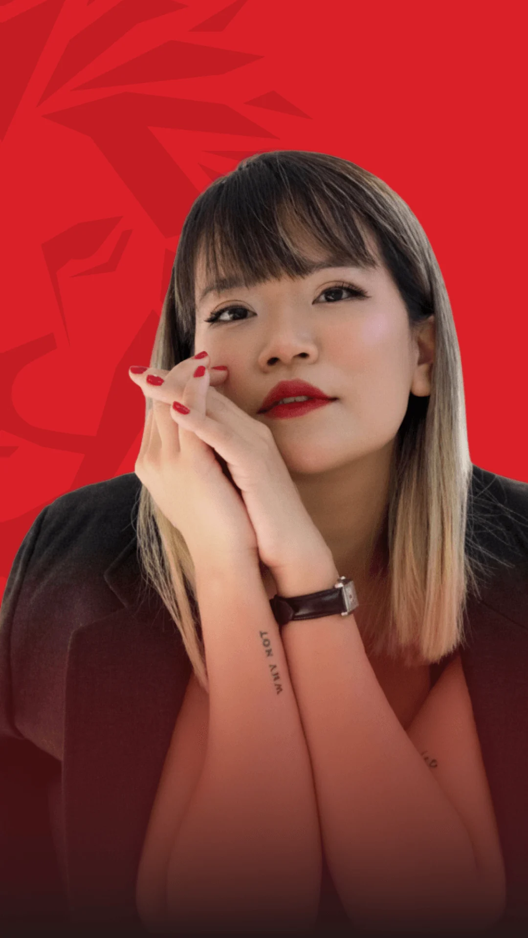 A young woman in a graduation-style pose, holding a small red flower against a red background.