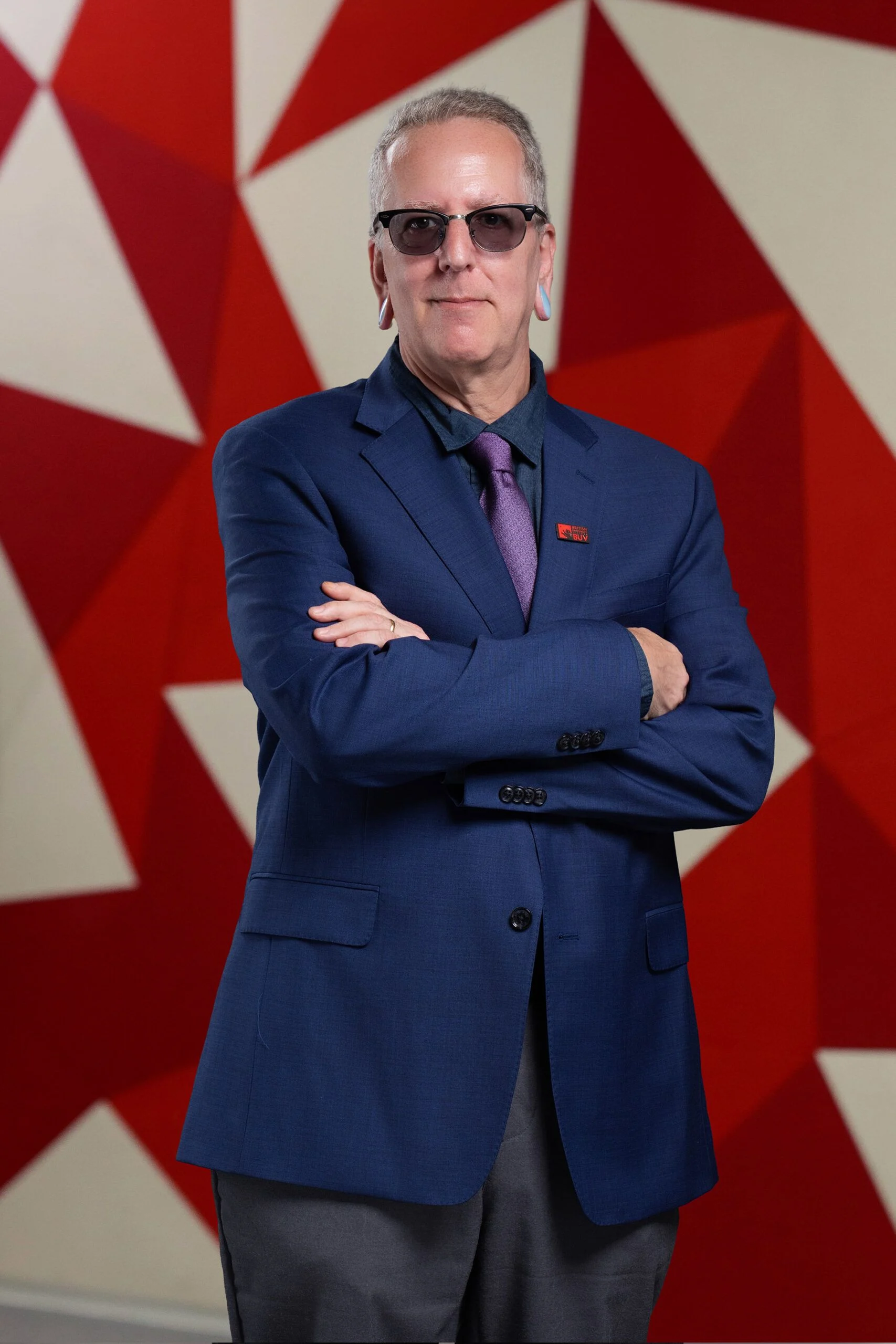 Scott David Cooper in a blue suit before a red geometric backdrop at British University Vietnam (BUV)