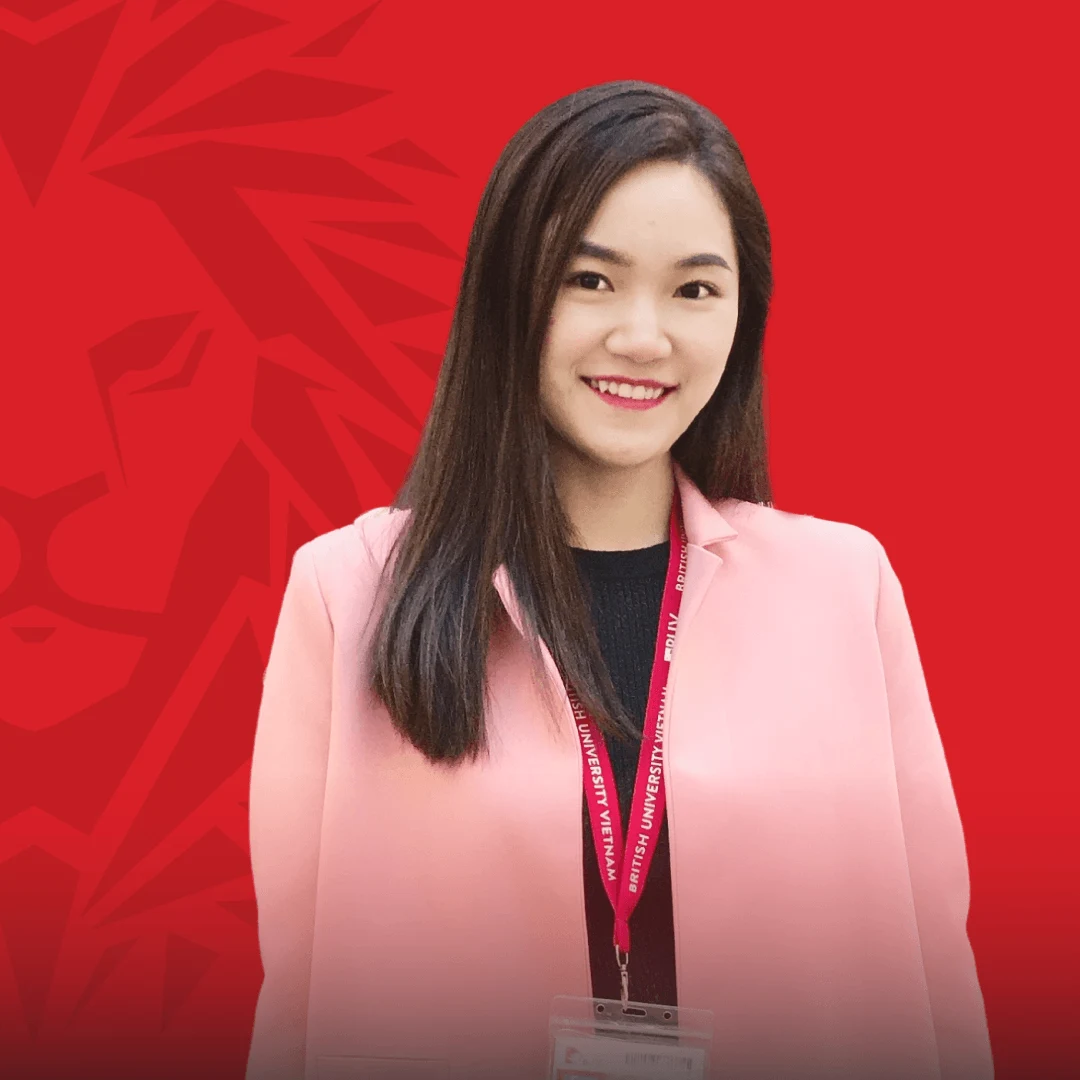 Portrait of a smiling BUV alumna wearing a pink blazer and university lanyard against a red background.