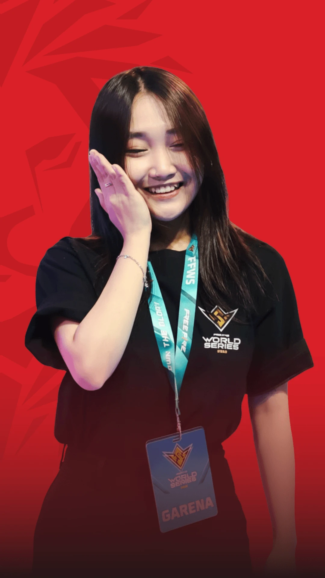 A smiling young woman wearing a lanyard and event medal, posing and waving in front of a red background.