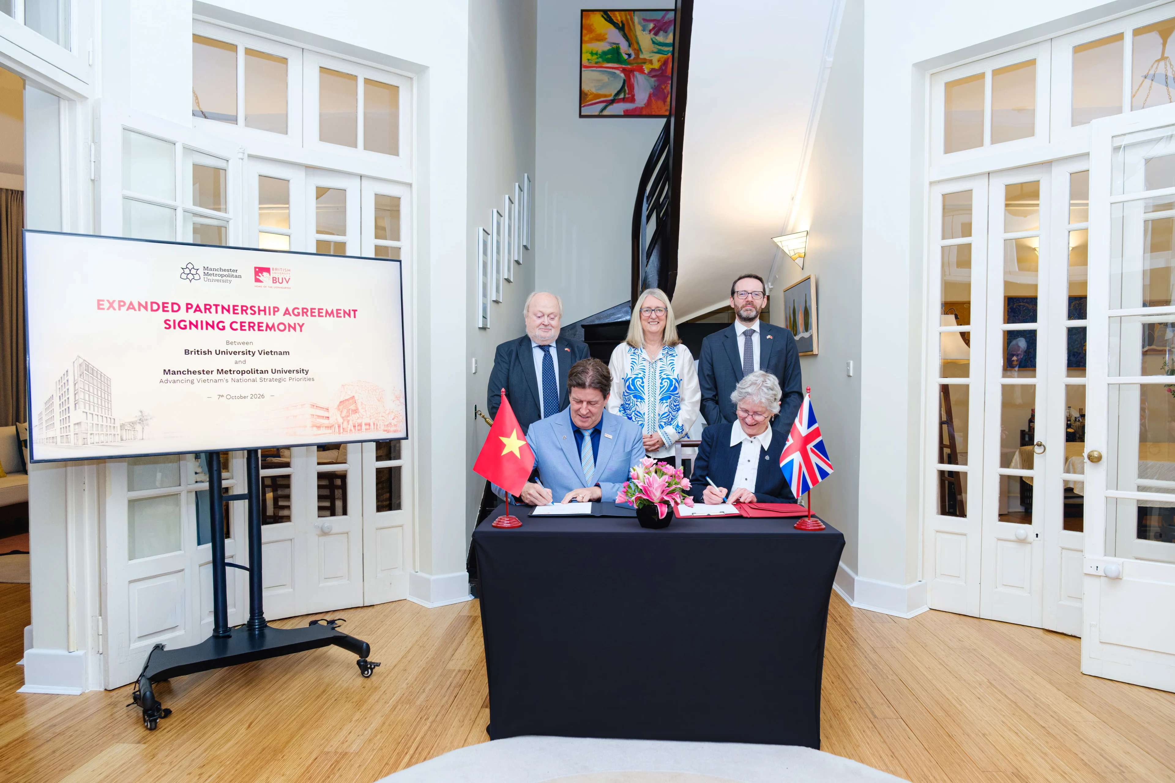 BUV and Manchester Metropolitan University sign an expanded partnership agreement at a ceremony featuring Vietnamese and UK flags.