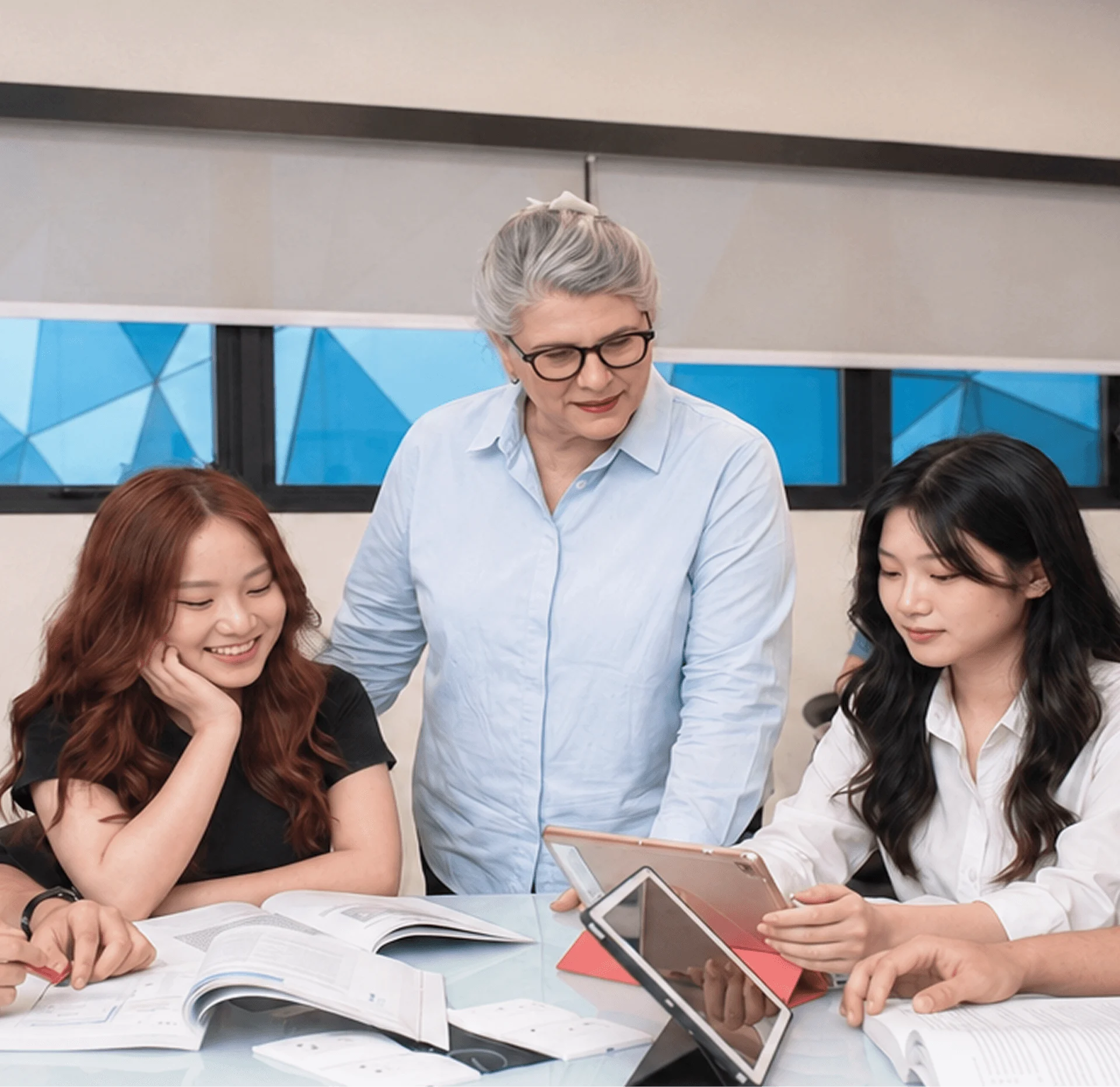 British University Vietnam (BUV) lecturer guiding students in a collaborative classroom session with books and tablets