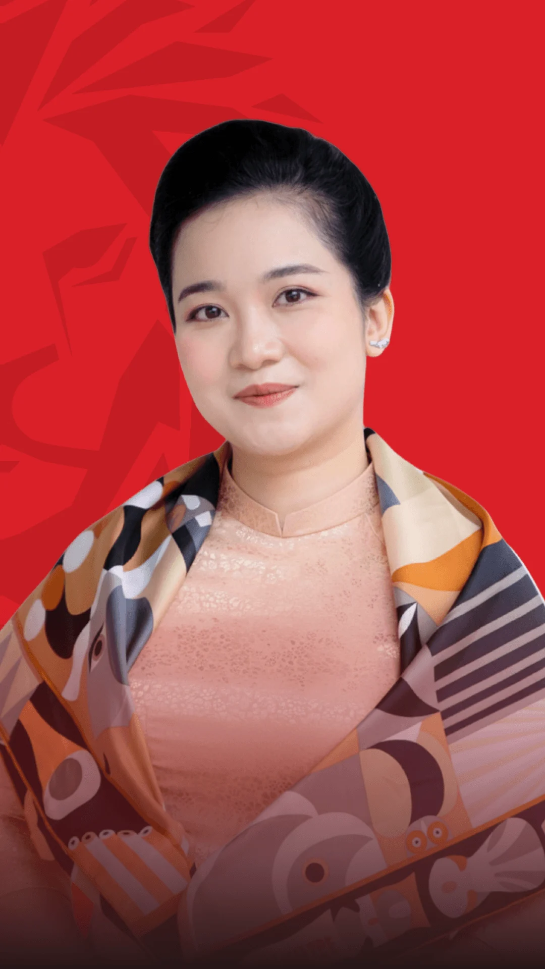 Alt text: **Chân dung nữ cựu sinh viên trên nền đỏ, mặc áo họa tiết và trang phục trang nhã**