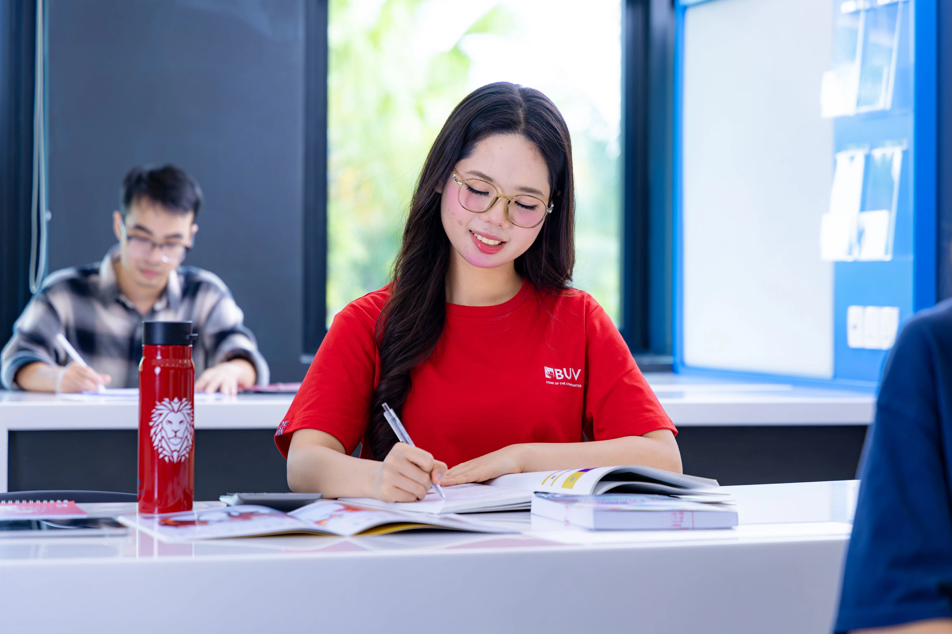 British University Vietnam student in a red BUV shirt studying in a bright classroom