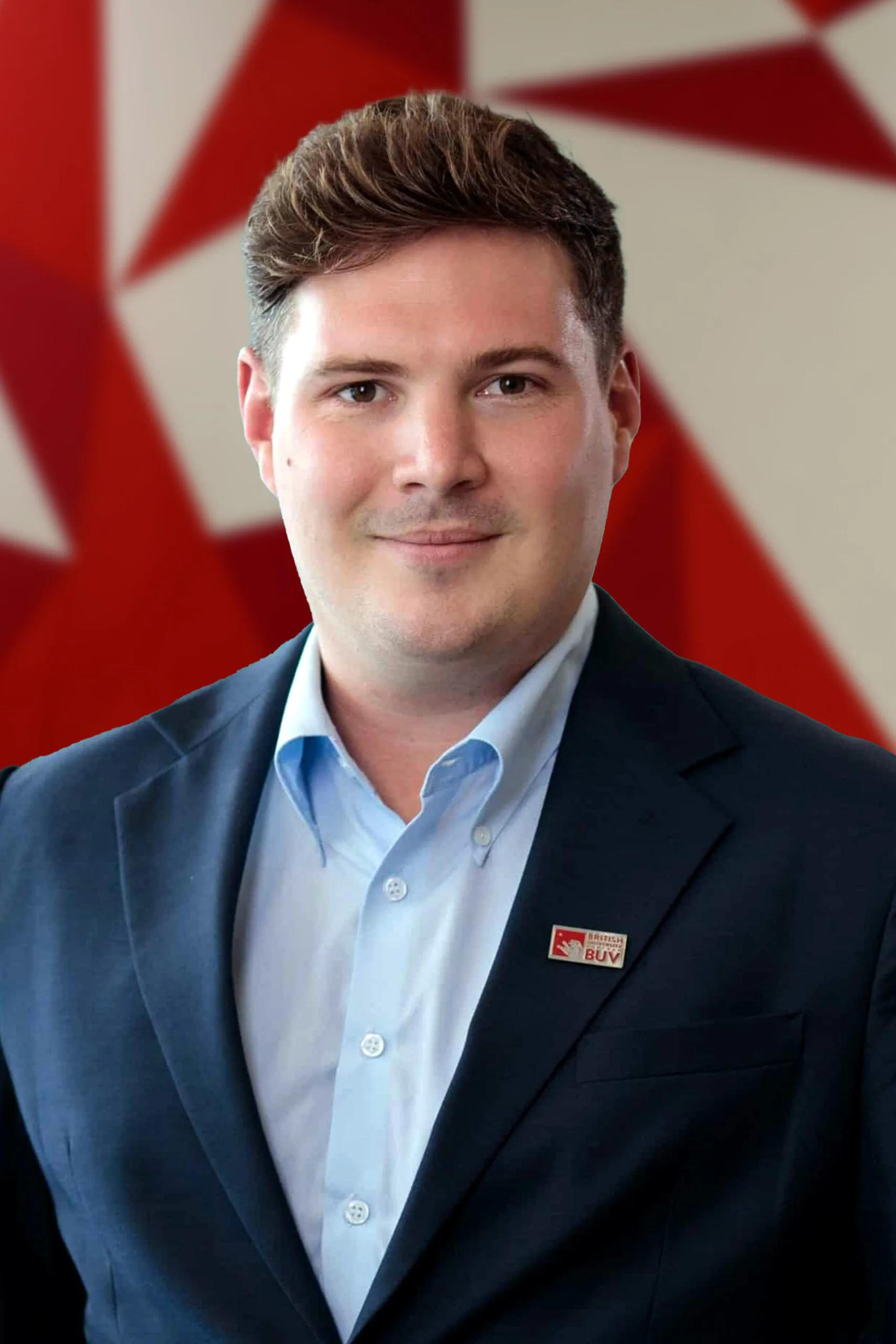 A professional headshot of Michael Lomax wearing a BUV blazer and light blue shirt in front of a red patterned background.