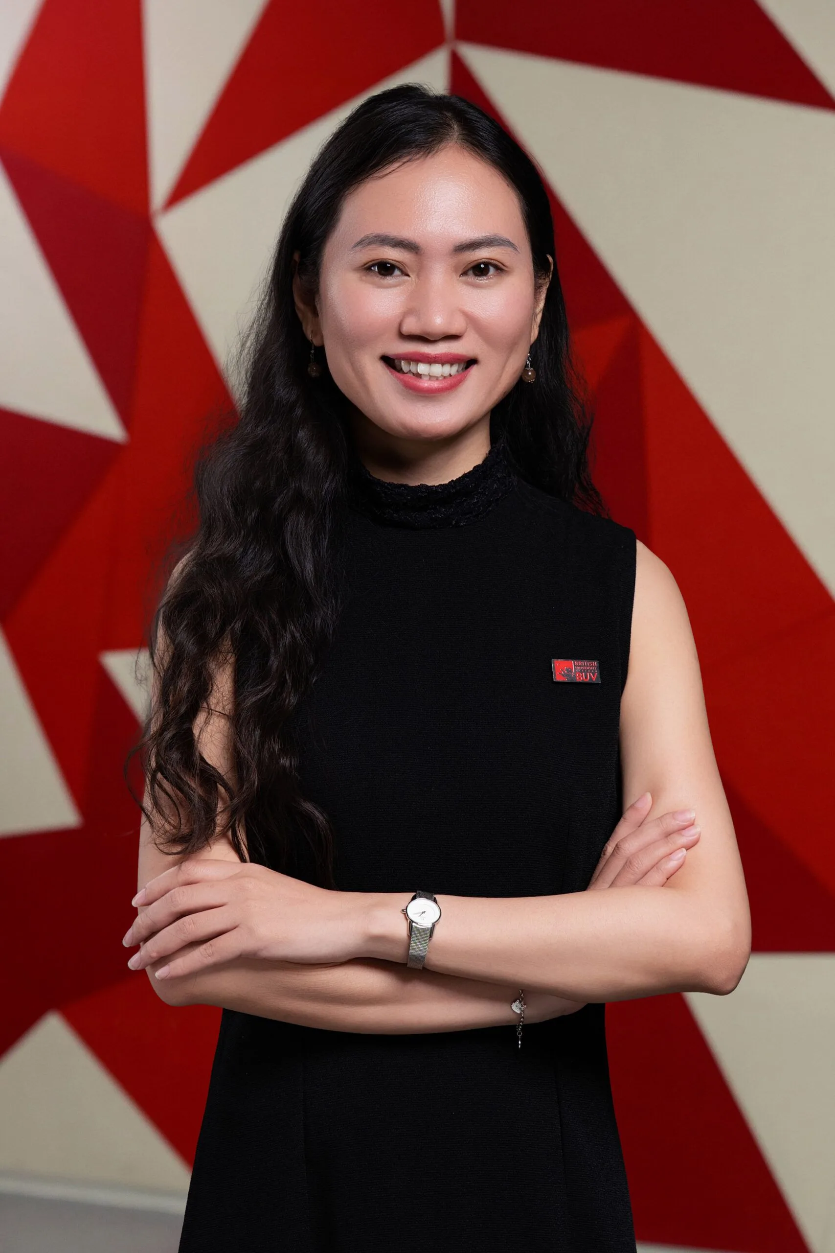 Dr Nguyen Quang Minh Nguyet of British University Vietnam smiling against a red geometric backdrop