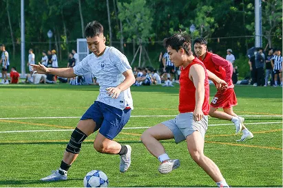 BUV students competing in a football match on an outdoor sports field during campus activities