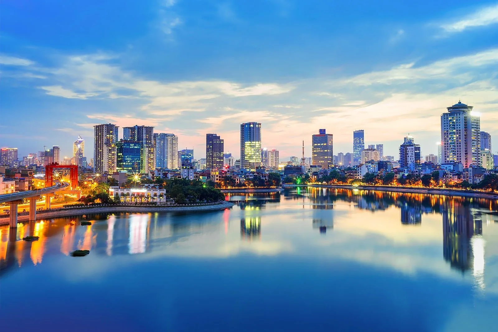 Ho Chi Minh City skyline at dusk, with illuminated high-rise buildings reflected on the Saigon River.