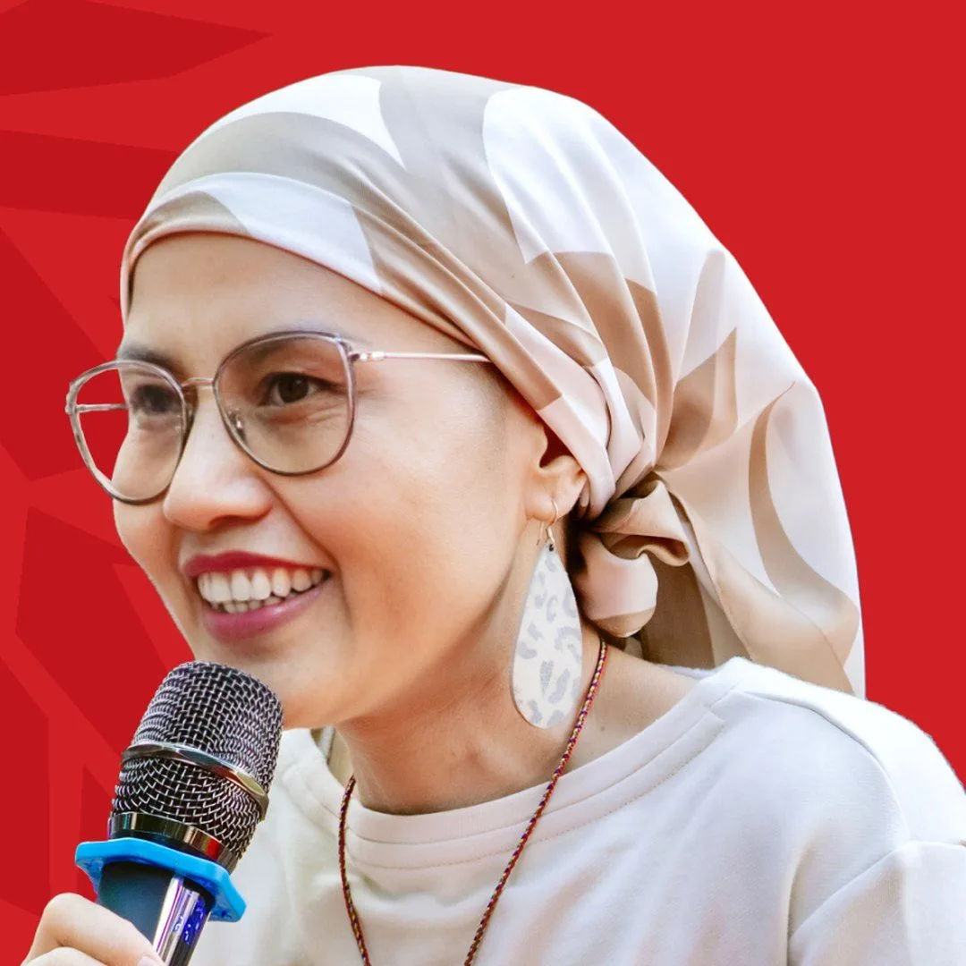 BUV alumna Kim Chung, known as Lionhearted, smiling and speaking into a microphone against a red background.