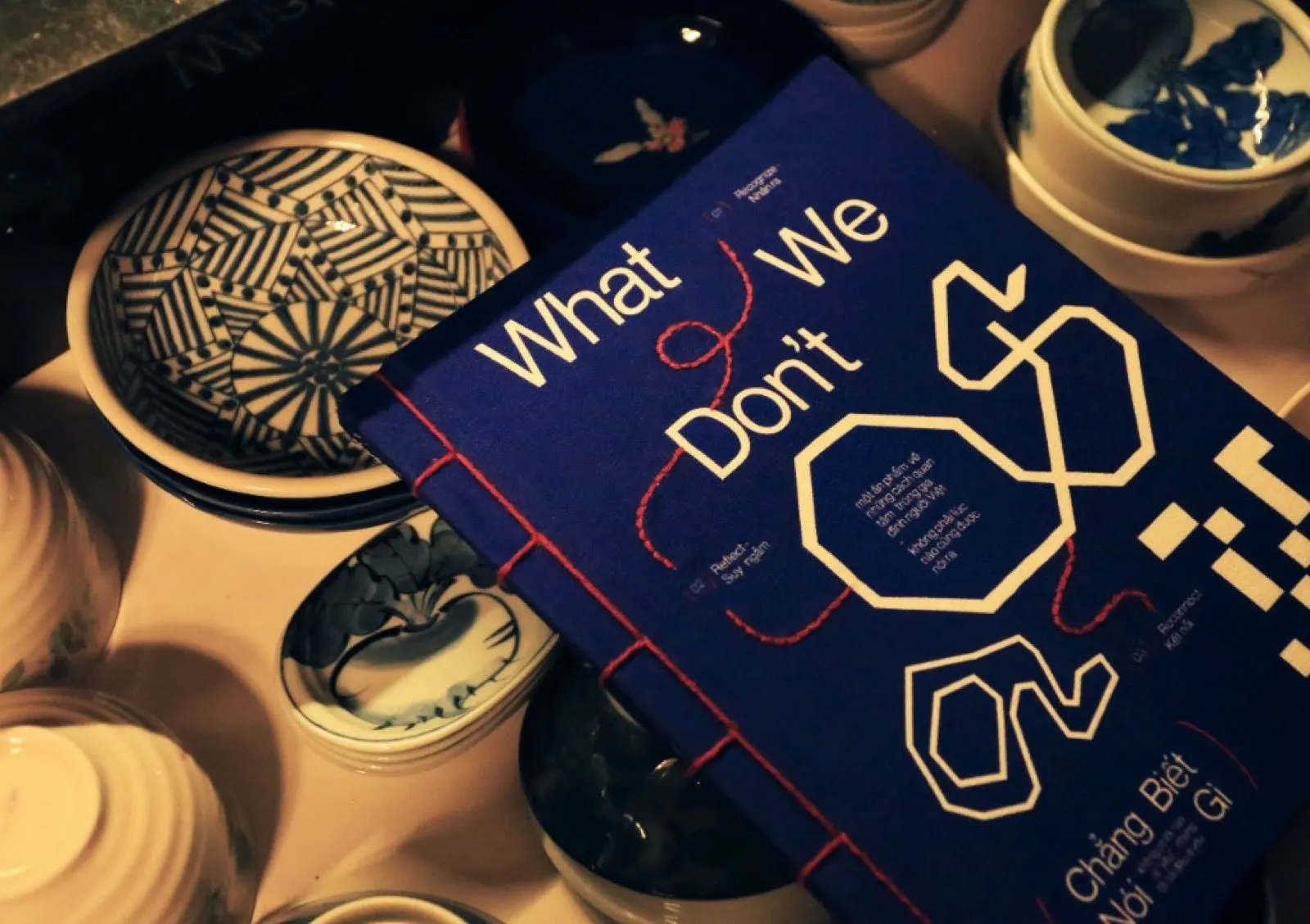 “What We Don’t Say” (Chẳng Biết Nói Gì) art book displayed among handcrafted ceramic bowls and pottery