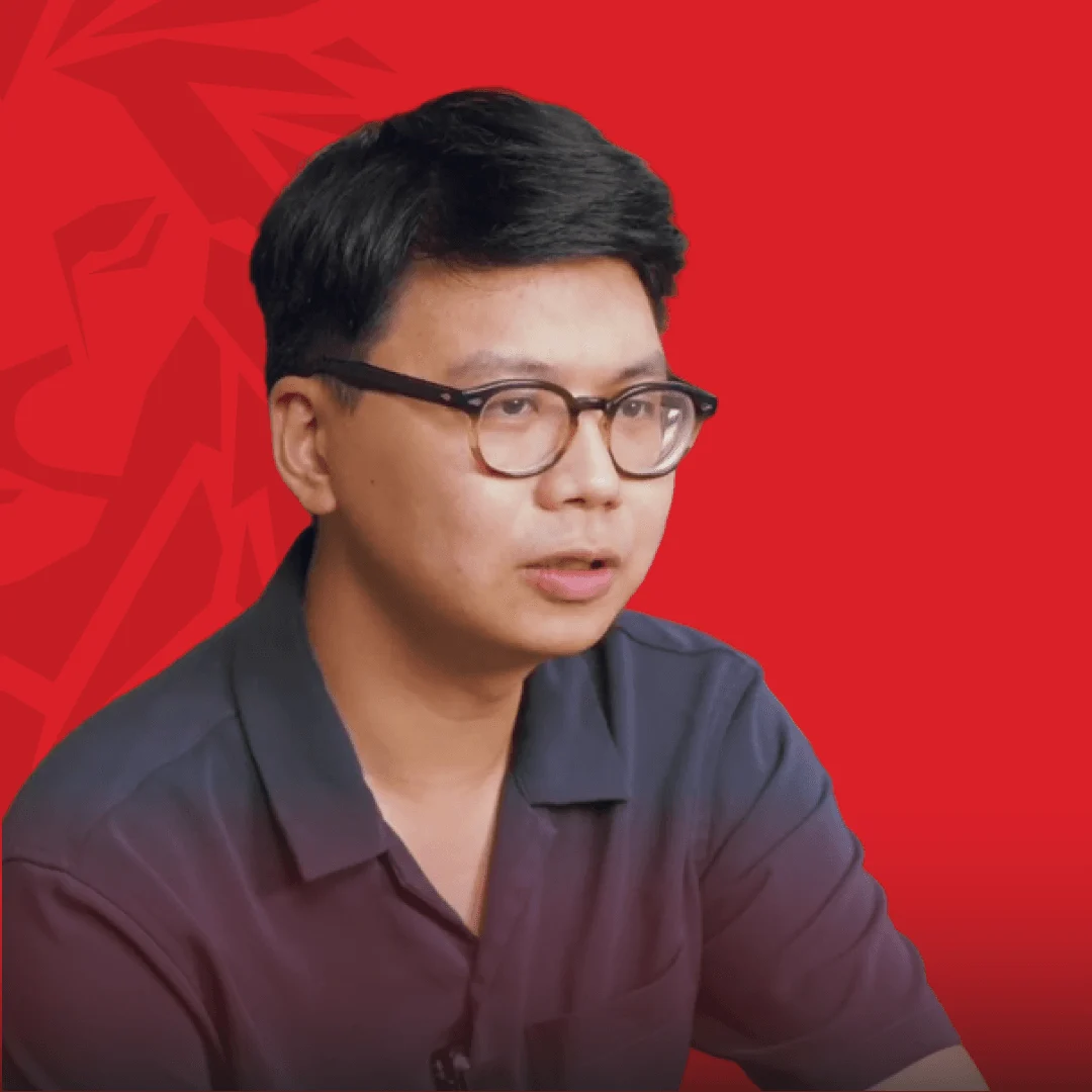 Portrait of Nguyen Minh Thang, a young man wearing glasses and a dark shirt, against a red background with an abstract pattern.