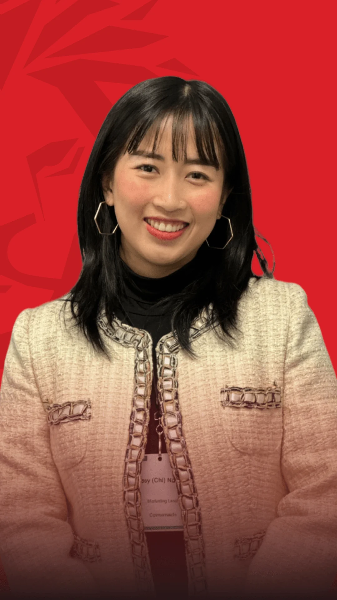 Portrait of a smiling female BUV alumni wearing a light-colored traditional-style outfit, photographed against a red background.