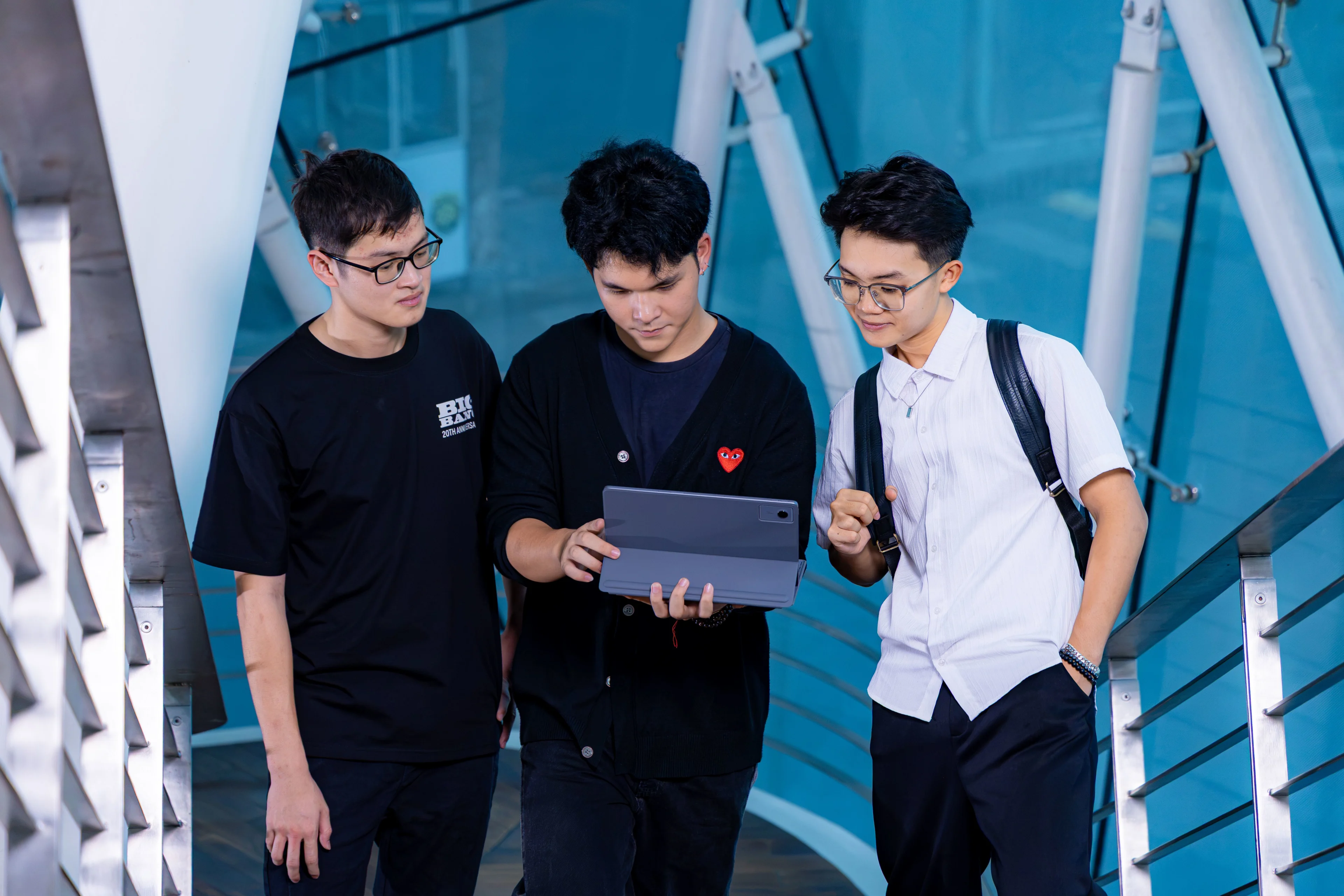 Three BUV students collaborating on a tablet at the British University Vietnam campus