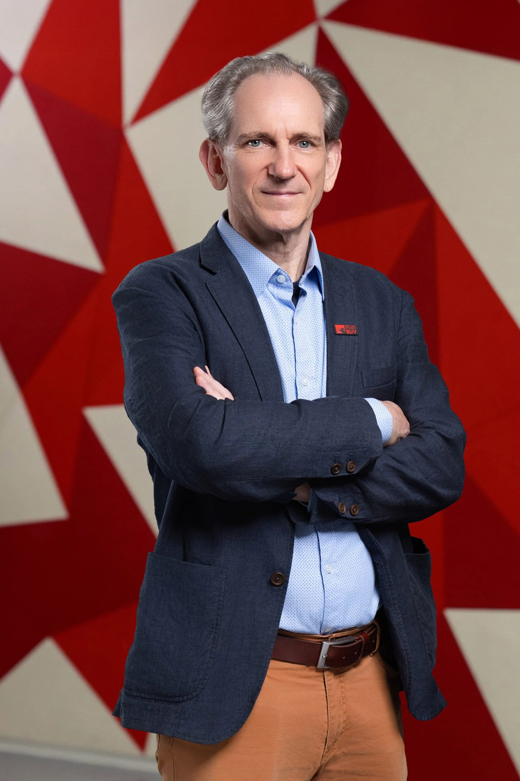 Sven Pfrommer wearing a BUV pin at British University Vietnam against a red geometric backdrop